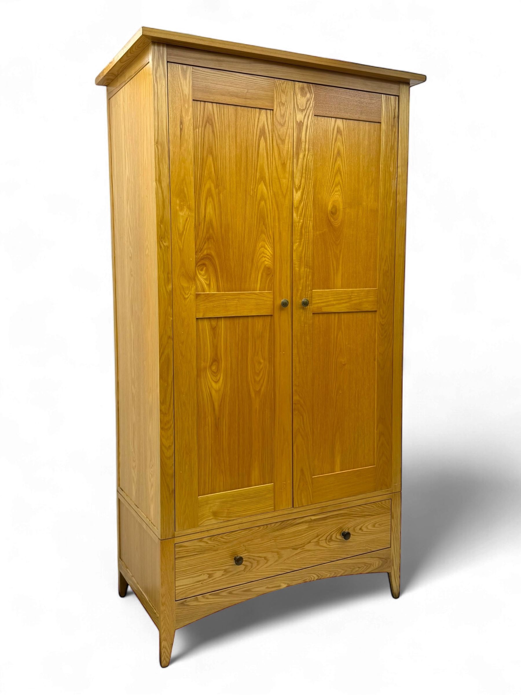 Contemporary light oak double wardrobe, projecting cornice over two panelled doors enclosing hanging rail and shelf, above full-width drawer, on shaped stile supports
