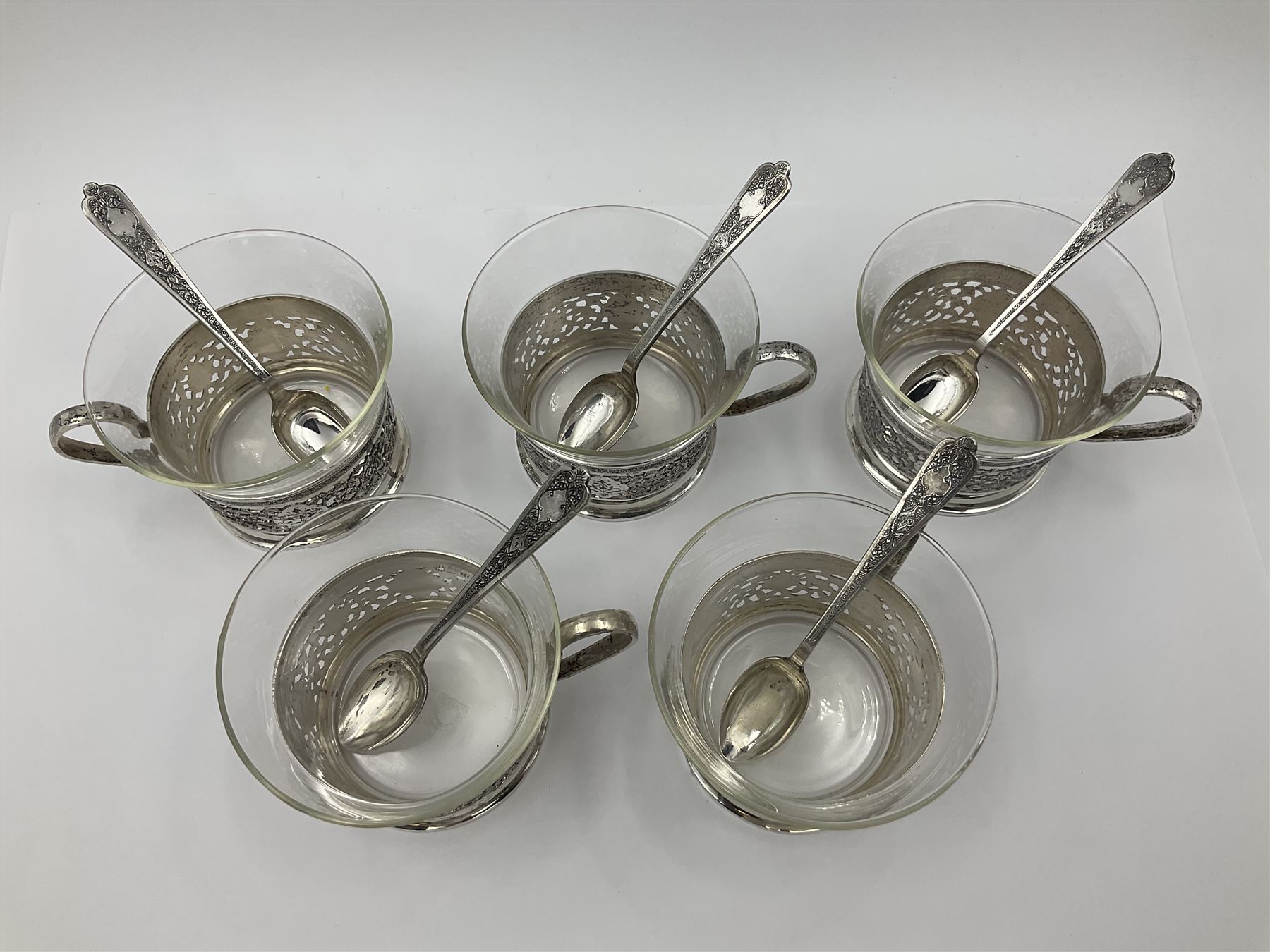 Early/mid 20th century Persian silver tea service, comprising circular serving tray, teapot, twin handled sucrier and cover, milk jug, five tea glasses with six silver holders, six tea spoons, and pair of sugar tongs, each profusely chased with foliate arabesque decoration, each bearing marks including 84 for 840 fineness, tray D40cm, teapot H16cm