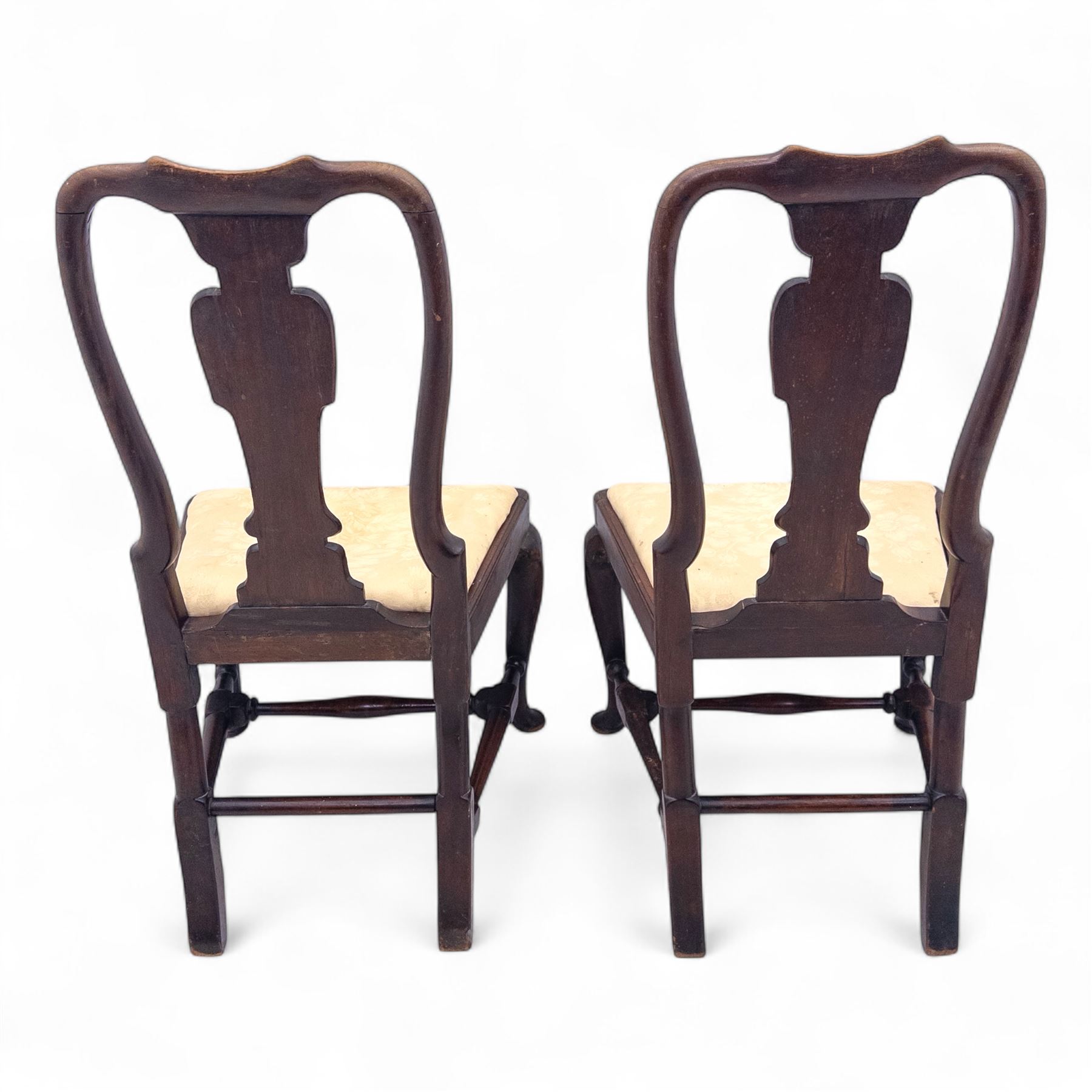Pair of early 18th century walnut side chairs, vase-shaped splats beneath shaped top rails, drop-in seats upholstered in floral damask, on cabriole front legs terminating in pad feet, united by turned stretchers