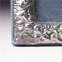 Embossed silver photograph frame London 1985 aperture 12.5cm x 8.5cm, another with scroll top Birmingham 1921 13cm x 9cm and a circular frame Birmingham 1909 6cm