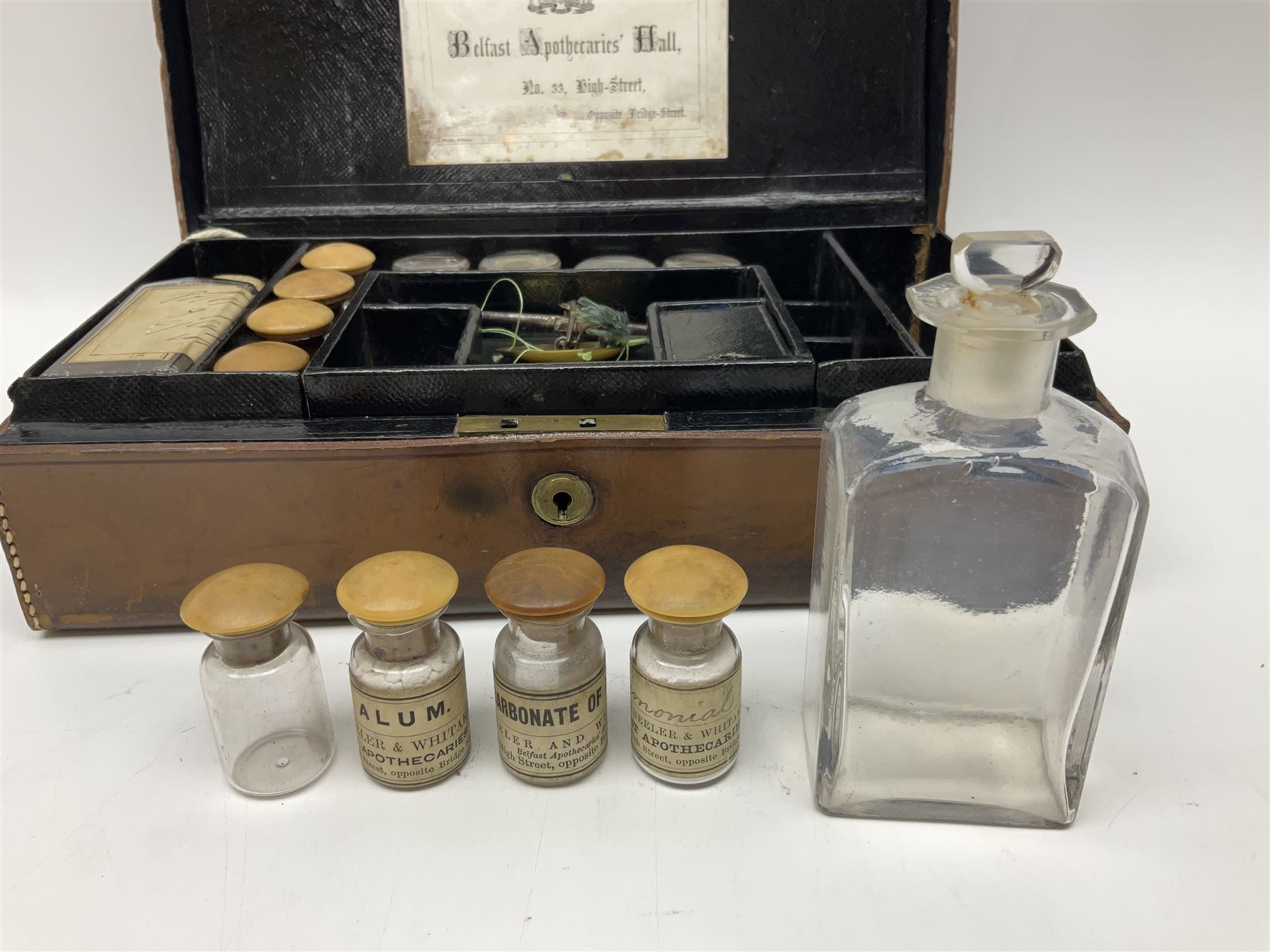 19th century apothecary leather carrying case, with key, the hinged lid opening to reveal seventeen glass medicine bottles with stoppers, most with chemist labels, gram scales, and domestic medicines booklet, H9cm, L27cm