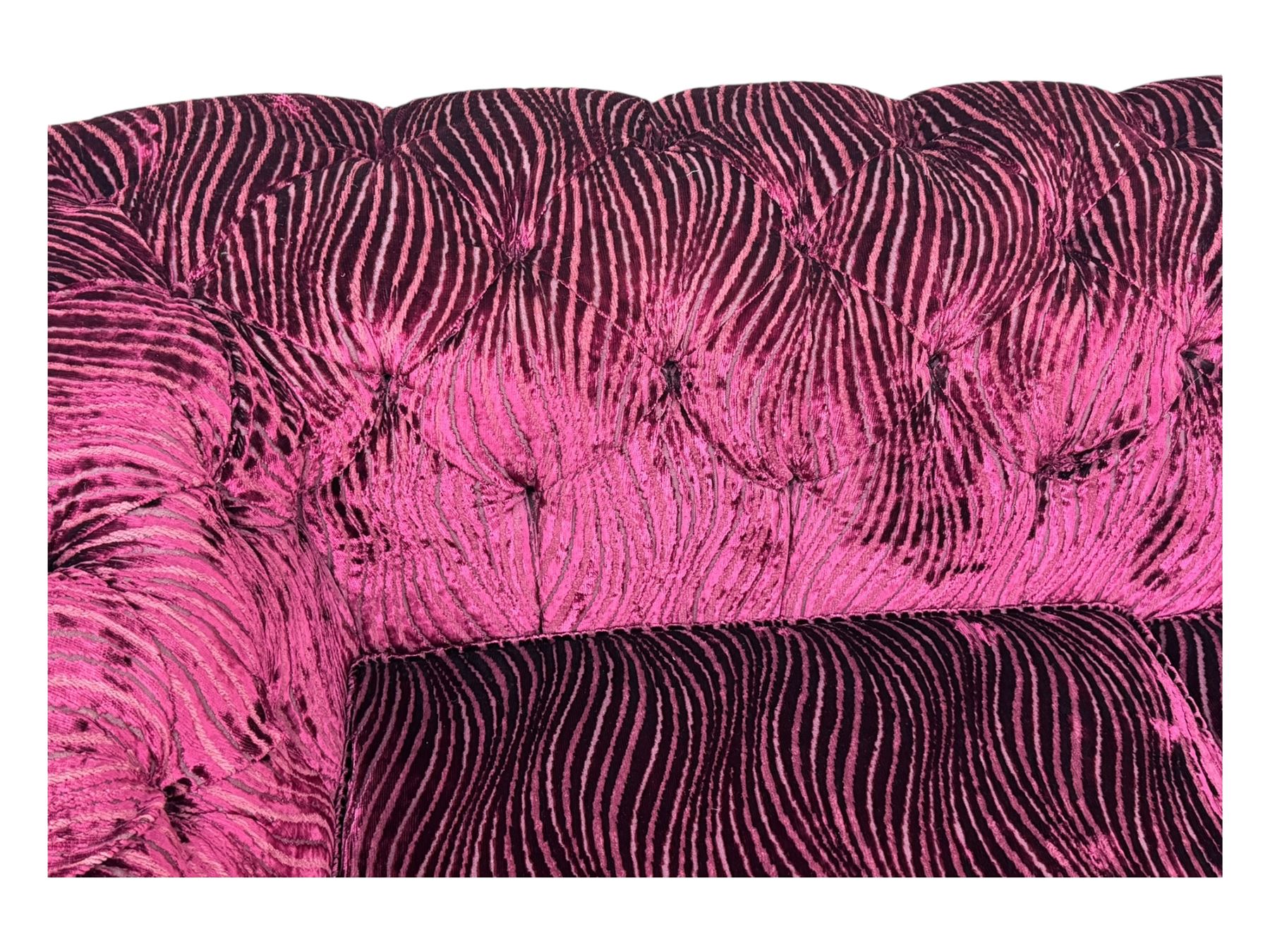 Contemporary Chesterfield design two-seat sofa, upholstered in fuchsia crushed velvet with a ribbed and tufted design, the rolled arms and deep-buttoned backrest raised on square block supports