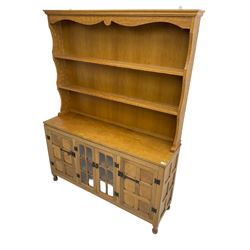 Yorkshire oak - adzed oak dresser, the rack with projecting cornice over shaped frieze and two shelves, the dresser fitted with central glazed double cupboard flanked by two panelled single cupboards, panelled sides