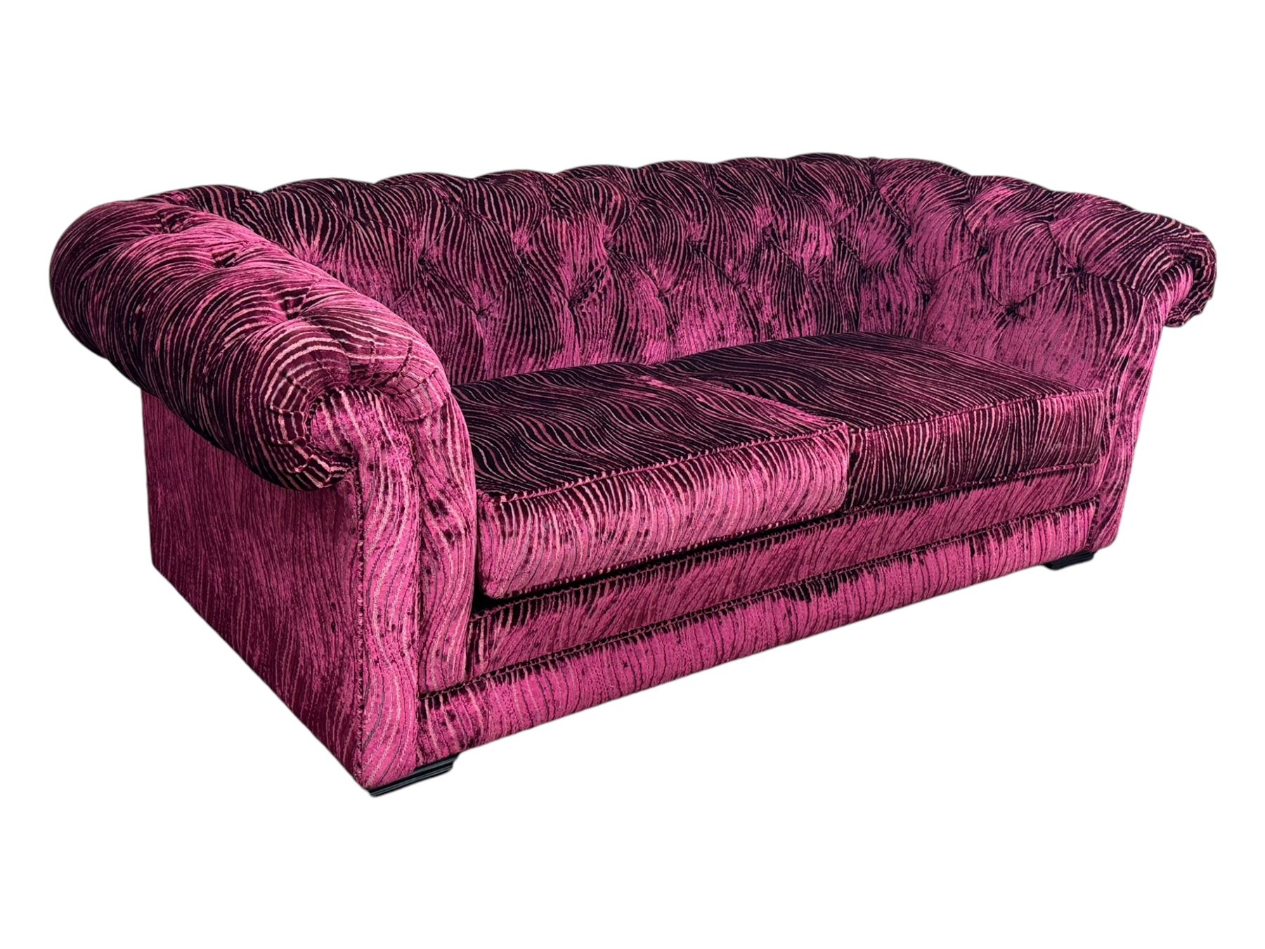 Contemporary Chesterfield design two-seat sofa, upholstered in fuchsia crushed velvet with a ribbed and tufted design, the rolled arms and deep-buttoned backrest raised on square block supports