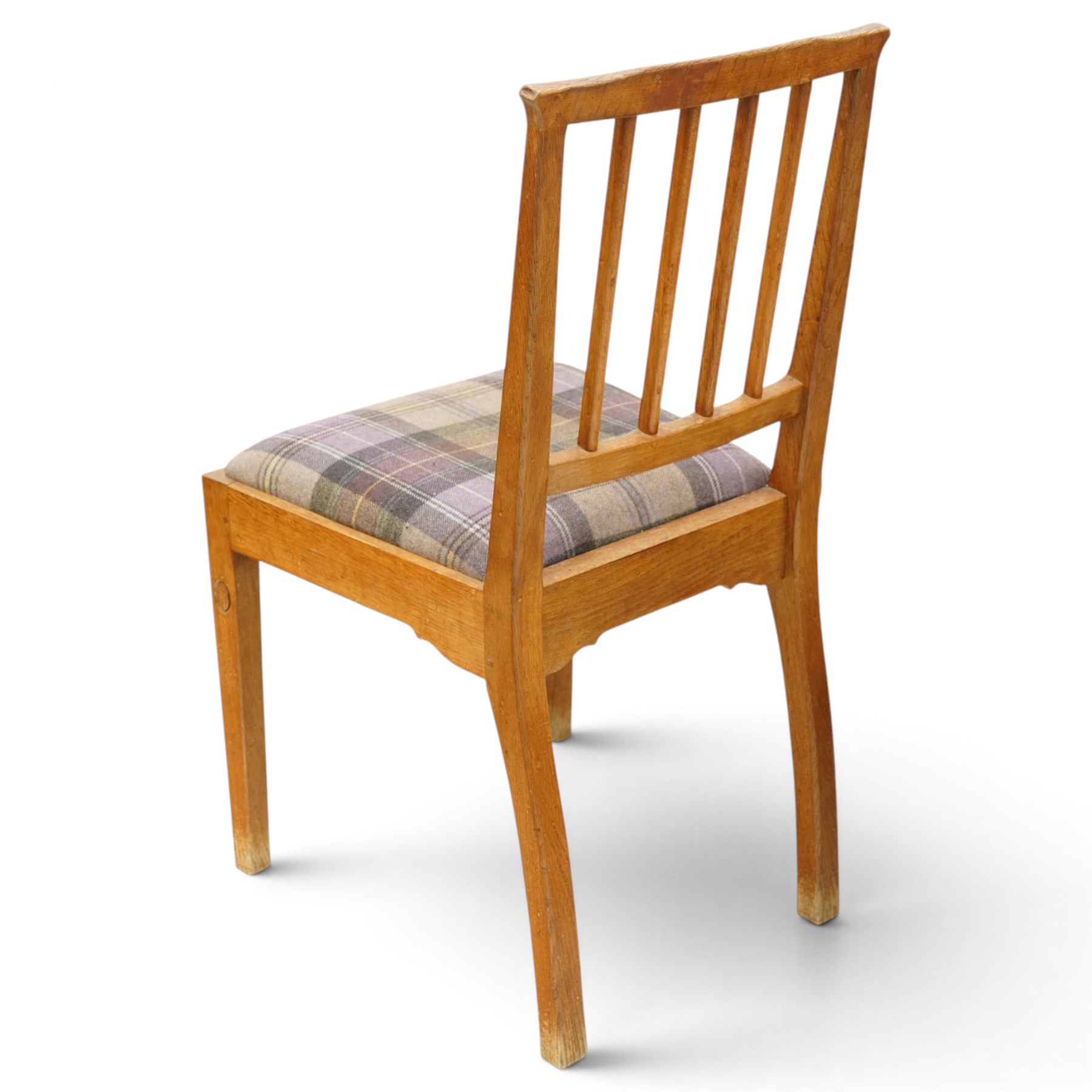 Acorn Industries - set of eight oak dining chairs, the shaped cresting rail over a fluted stick back, the drop-in seats upholstered in contrasting form with four pale mauve and four in purple tartan, raised on square supports, carved with acorn signature, by Alan Grainger, Brandsby