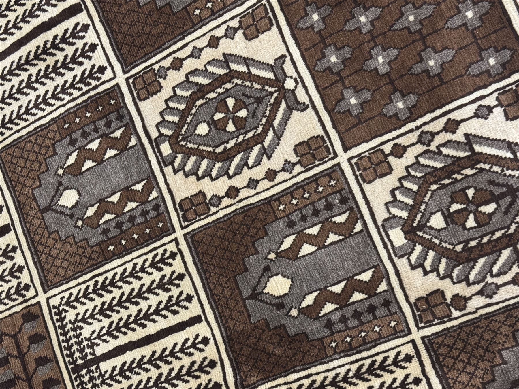 Mid-20th century Persian Bakhtiari rug, ivory ground with alternating dark brown and ivory panels featuring geometric and floral designs, bordered by a plain ivory band