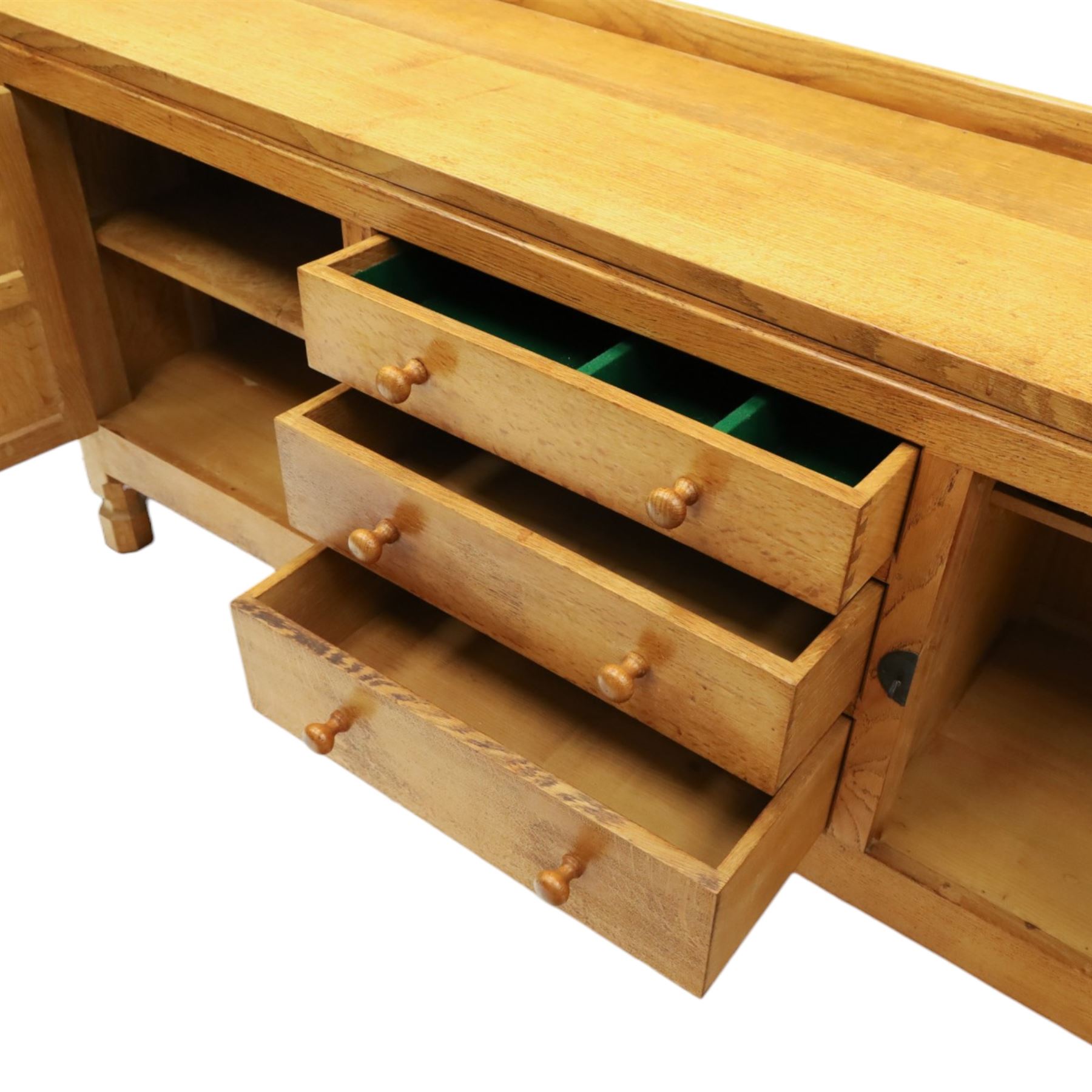 Mouseman - large adzed light oak sideboard, the rectangular top with raised galleried back, fitted with three central drawers flanked by panelled cupboards enclosing shelves, with wrought iron fittings, raised on octagonal feet, with signature carved mouse, by the workshop of Robert Thompson, Kilburn