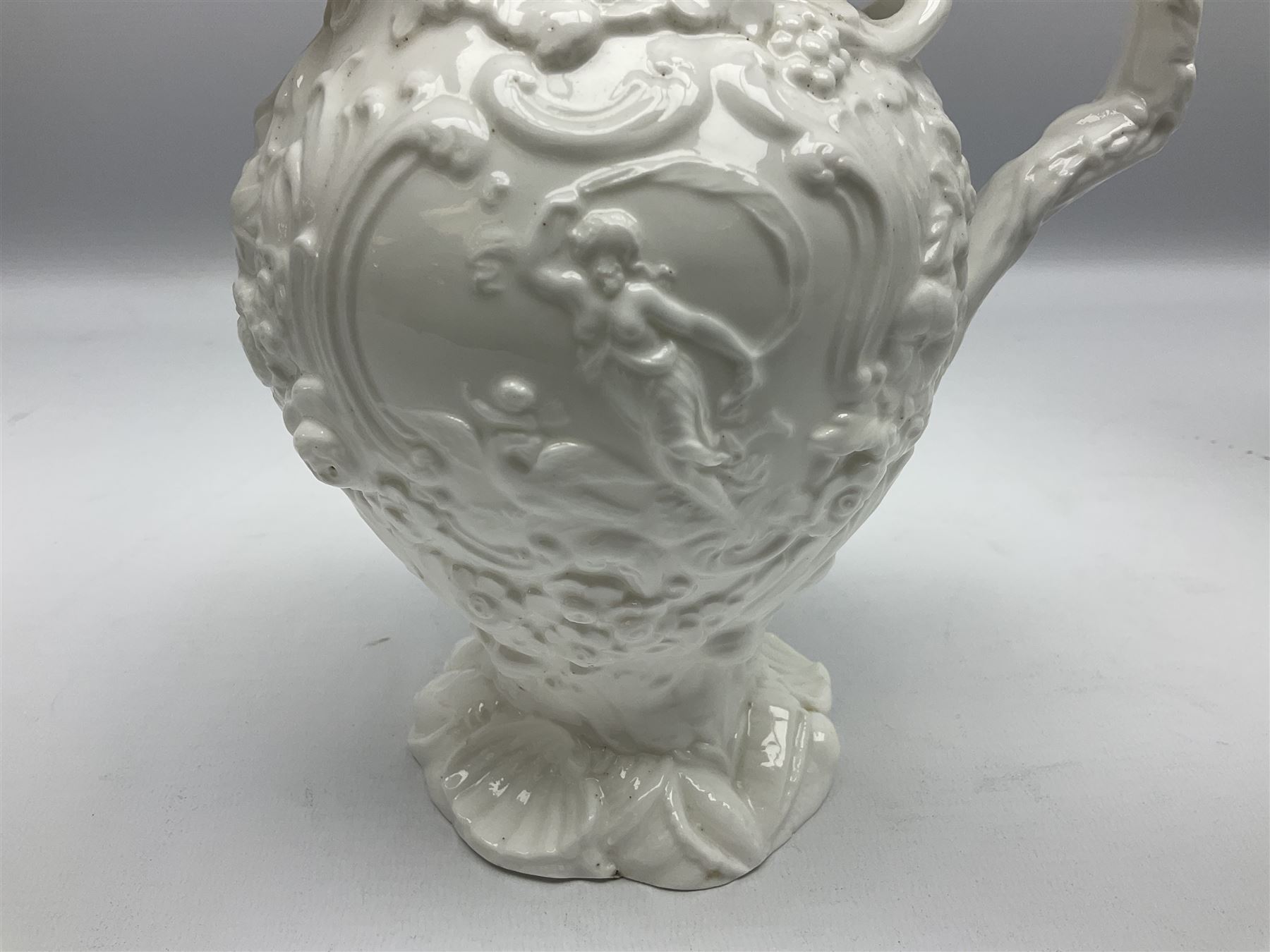 Pair of early/mid 19th century Copeland and Garrett white glazed pitchers, modelled in the Georgian style and moulded with the figures of Venus the Roman Goddess of Love, and Aurora the Roman Goddess of Dawn, within C scroll borders and foliate surround, the naturalistically modelled handle leading to a fruiting vine beneath the rim, upon a spreading base moulded with seashells, with printed green crowned wreath mark beneath, H20cm