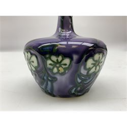Three Minton Secessionist vases, with tube-lined stylised flower decoration, two upon a red ground and third upon a purple ground, all with printed mark to base 'Minton Ltd, No. 33', H13cm