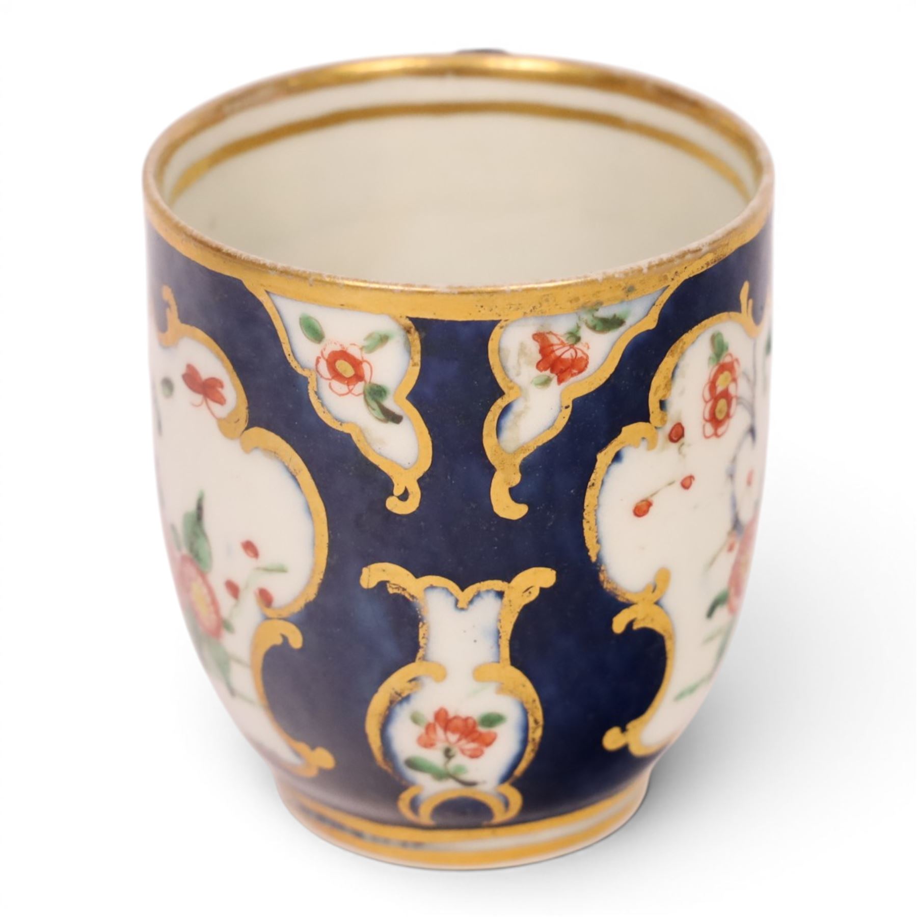 18th century Worcester coffee cup and saucer, circa 1770,  painted with shaped panels of chrysanthemums and banded hedges on a blue scale ground with gilt detail to the rim, mark beneath, H8cm 