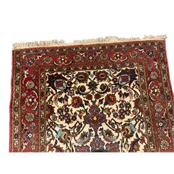 Persian red ground rug, central floral pole medallion within an ivory field decorated with floral patterns, the guarded border with repeating stylised plant motifs