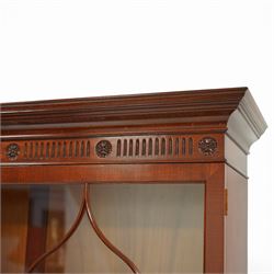 William Tillman - Early 20th century mahogany display cabinet, moulded cornice above a frieze carved with roundels and fluting, pair of astragal glazed doors enclosing adjustable shelving, the lower section fitted with twin panelled cupboard doors centred with oval veneered panels, shaped apron and bracket feet