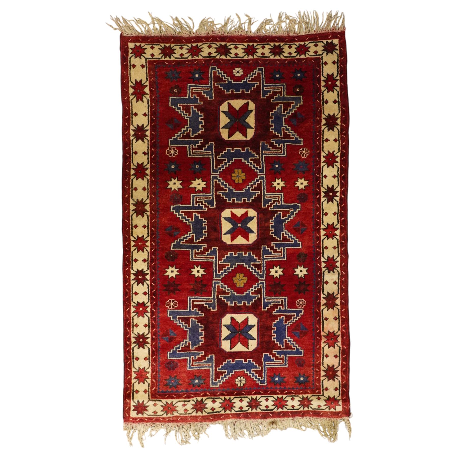 Caucasian Kazak hand-knotted rug, madder red ground with three large stepped geometric medallions in dark blue, ivory and red, surrounded by stylised star and flowerhead motifs, enclosed by ivory border with repeating eight-pointed stars, fringed ends