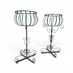 Matched pair of antique metal plant stands, each with circular strapwork basket tops, the scrollwork supports raised on an X-form base, in green painted finish with rustic patina