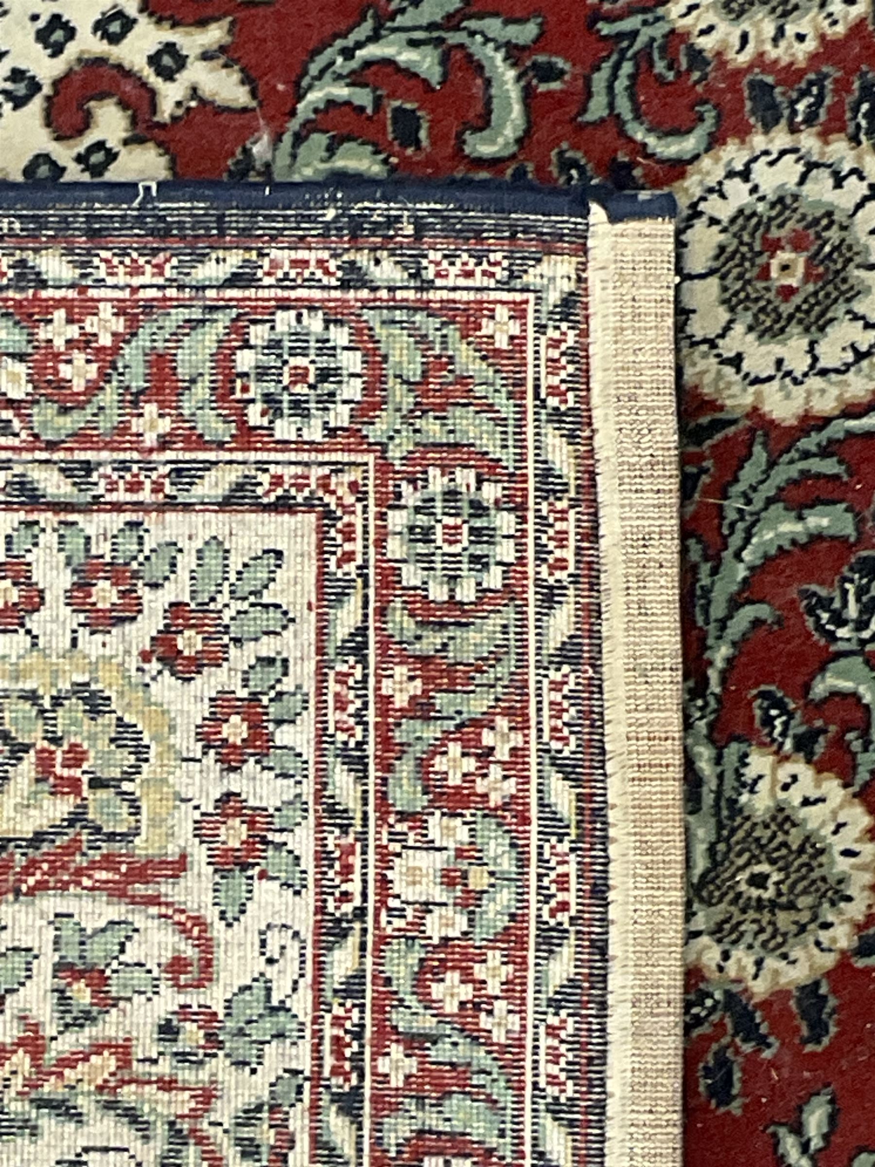Persian design crimson ground carpet, the central rosette medallion surrounded by scrolling leaves and flower heads, the spandrels decorated with floral design and scrolling foliage, repeating border within guard stripes