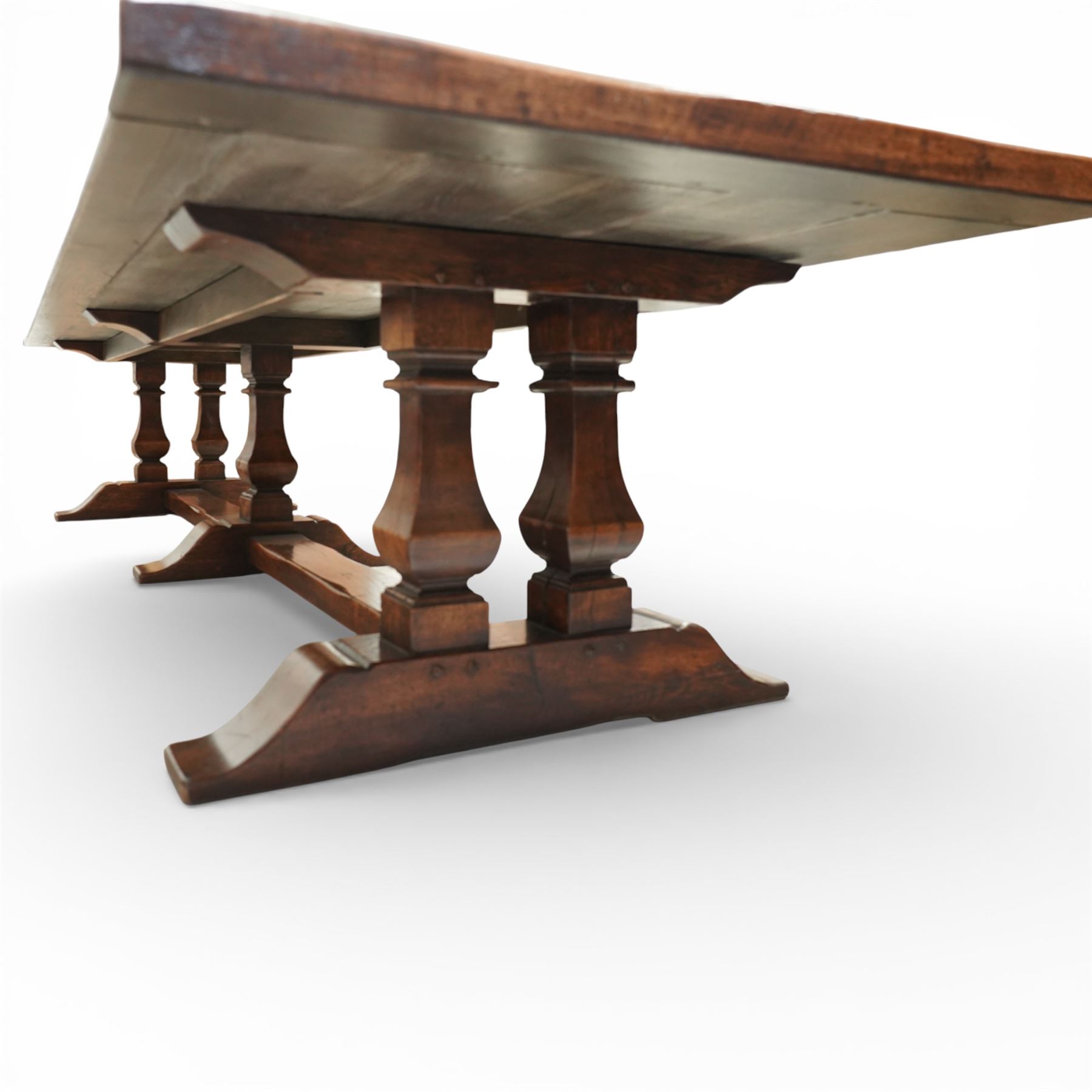 Country House 12' oak and fruitwood refectory dining table, the substantial rectangular plank top with cleated ends and chamfered edge, raised on twin trestle end square tapering and turned baluster supports with sledge feet and chamfered united by a long stretcher rail