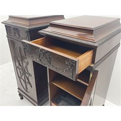 Pair early 20th century Hepplewhite style mahogany pedestal cabinets, cavetto moulded top with foliate carved edge over secret frieze drawer with applied trailing floral and ribbon decoration, each with button release underneath, oval panelled door with trailing harebell and central flower head motif decoration enclosing shelves, fitted cutlery drawer and lined cellarette drawer, on turned acanthus carved feet