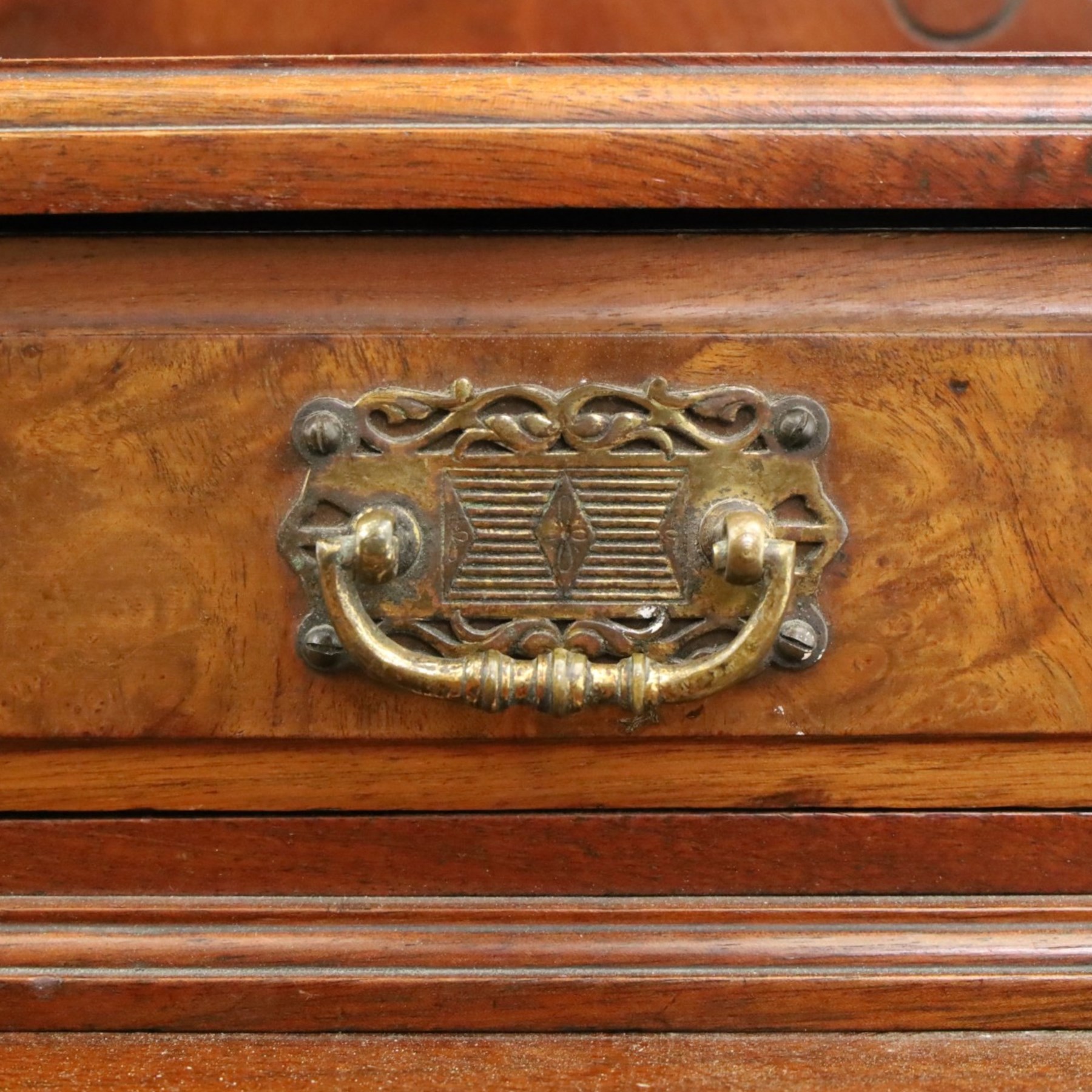 Late Victorian figured walnut and mahogany dressing table, raised swing-mirror back over trinket drawers, fitted with two drawers with brass Aesthetic Movement handles, on ring-turned supports with ceramic castors