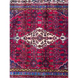 Northwestern Persian Hamadan hand-knotted rug, madder red field with a lozenge medallion enclosing an ivory centrepiece, indigo spandrels within an ivory border of stylized floral motifs between multiple guard borders 
