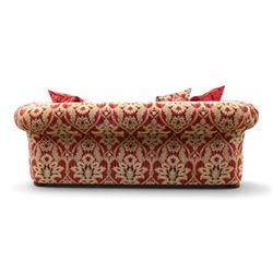 Tetrad - grande two seat 'Elgar' sofa of traditional Chesterfield shape with rolled arms, upholstered in red and gold foliate patterned fabric with matching loose and scatter cushions, on compressed bun feet