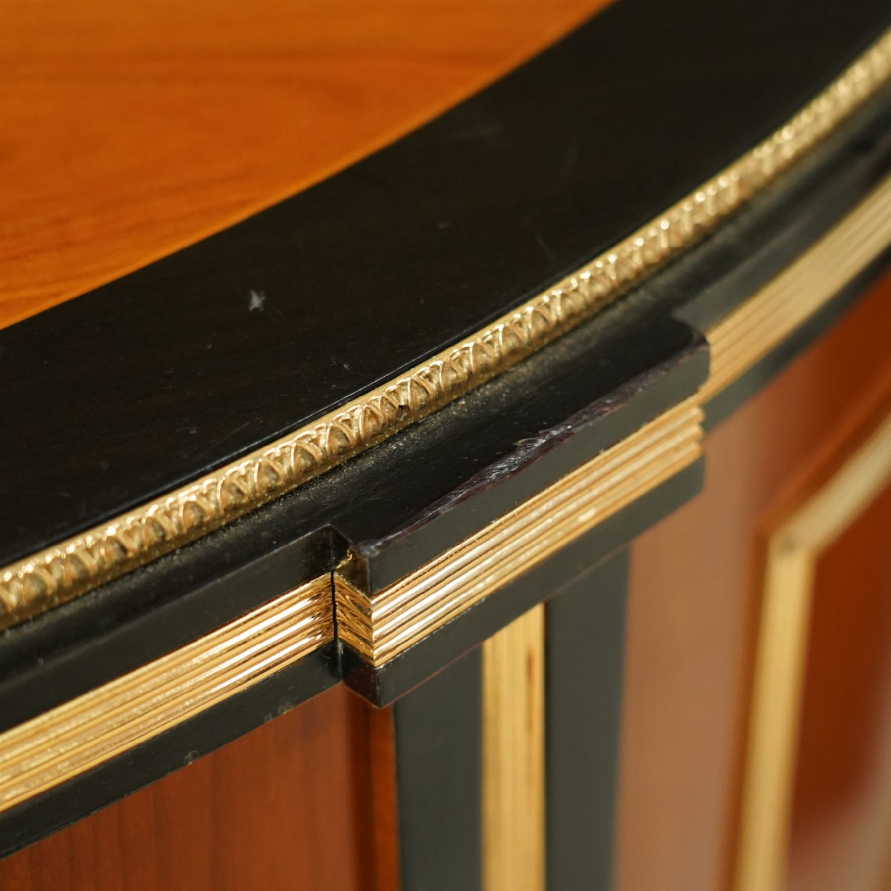 Colombo Mobili - Pair of Italian designer cherrywood art-deco inspired demi-lune commode cabinets, the shaped top with ebonised inlay and gilt brass repeating anthemion beading above a gilt brass reeded moulding, over three long drawers with gilt brass geometric panel mounts, flanked by cupboard doors with diamond motif, raised on tapering square supports 