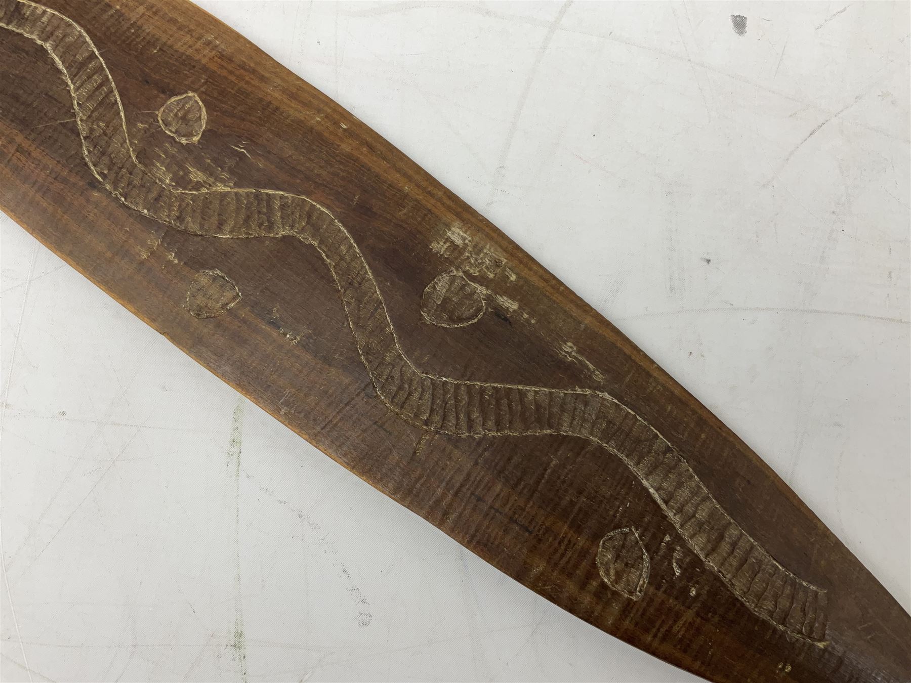 Australian aboriginal woomera spear thrower incised/carved with a wavy line and dots L69cm; and two boomerangs, one with carved geometric decoration (3)