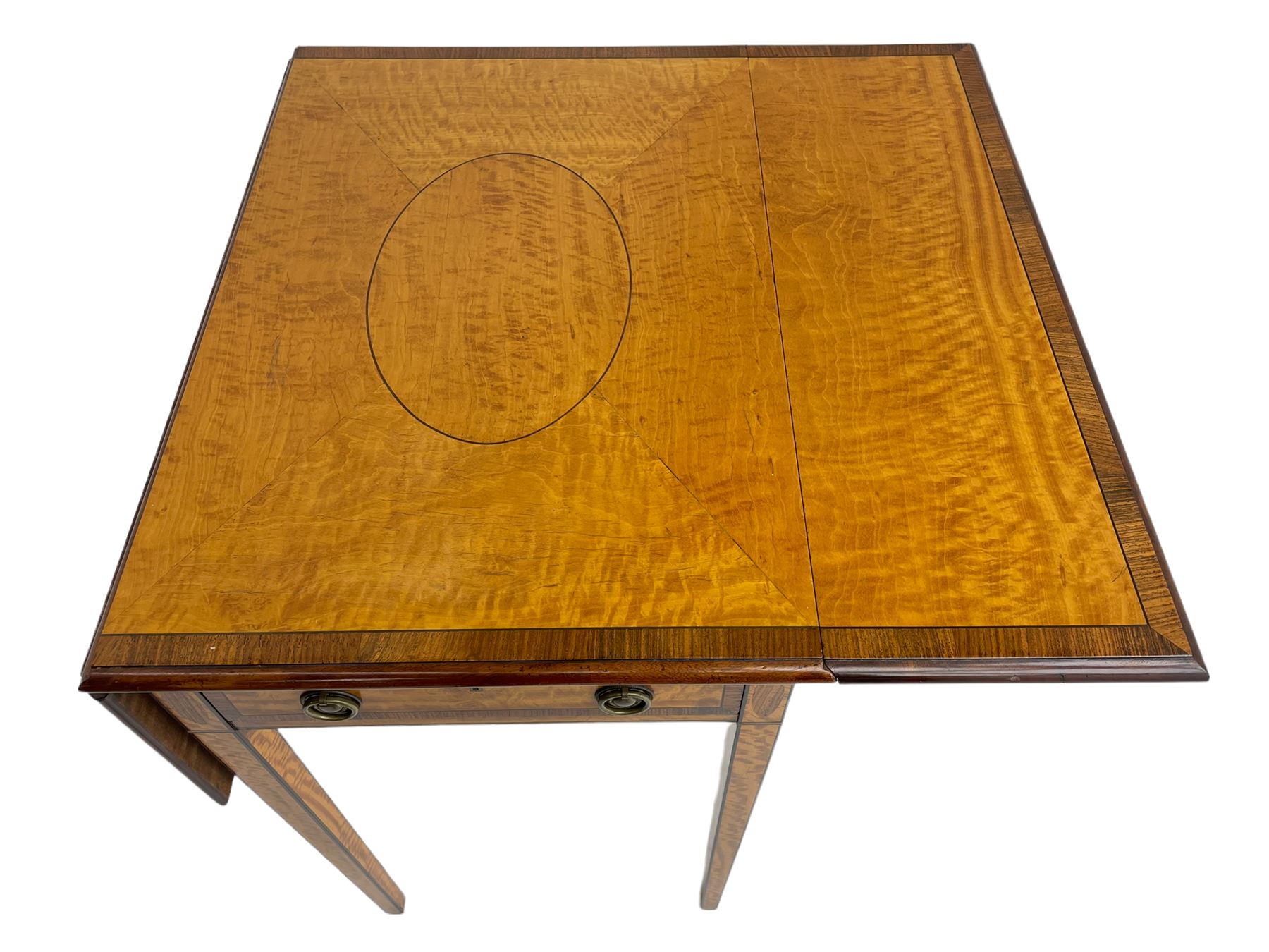 Mid-to-late 20th century Sheraton style satinwood Pembroke table, the drop leaf top with segmented veneers and central oval panel with ebony stringing, crossbanded in rosewood and with edge moulding, single short drawer to one end and faux drawer to other, square tapering supports