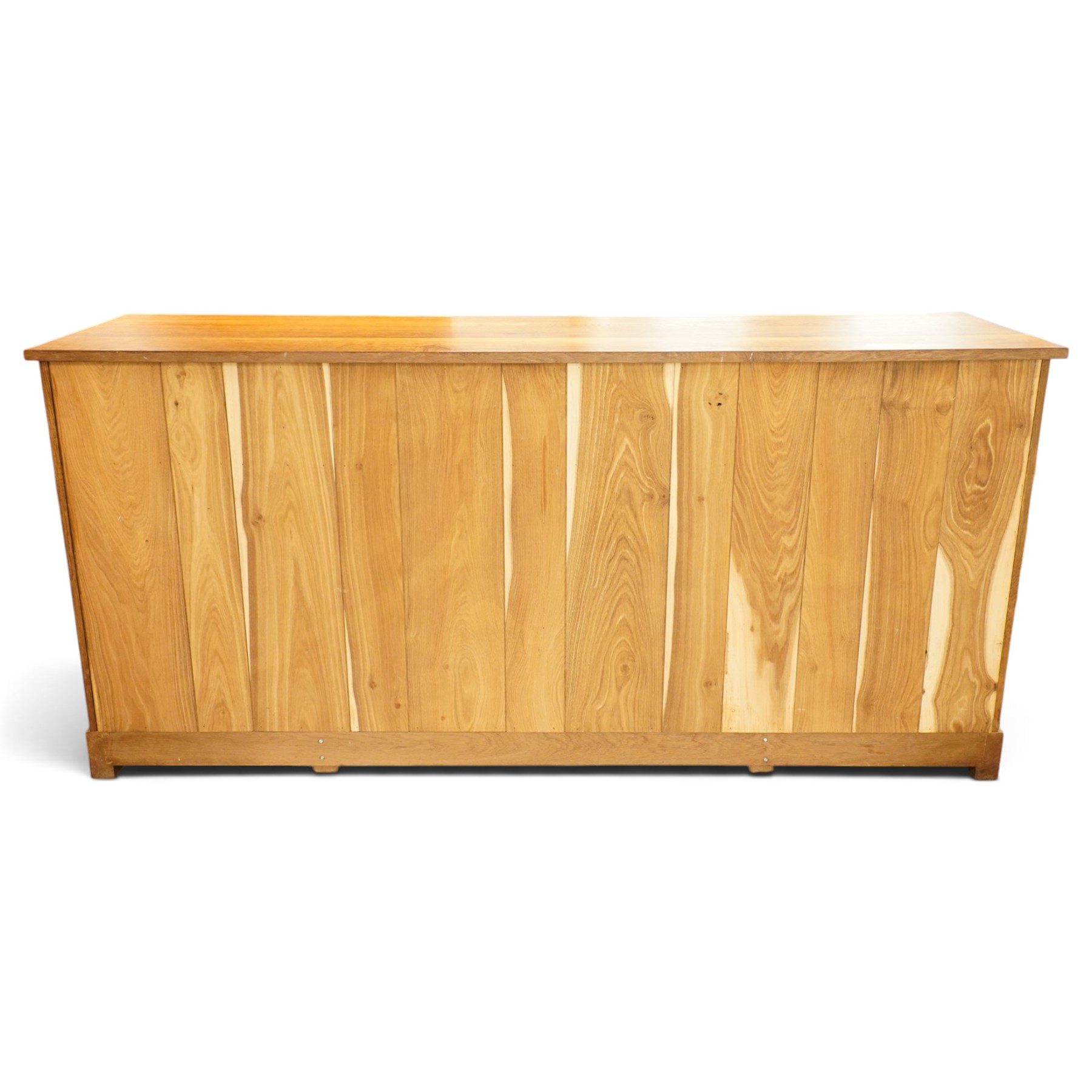 Acorn Industries - oak dresser base or sideboard, the rectangular top over three drawers with protruding oak handles, over four panelled cupboard doors enclosing a single shelf, raised on stepped feet, carved with acorn signature, by Alan Grainger, Brandsby