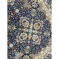 Persian indigo and pale gold ground rug, overall busy geometric design, the field decorated with hooked Hac and palmette medallions surrounded by densely patterned zig-zags and stylised foliate motifs, the border decorated with smaller Hac motifs, within multiple guard stripes 