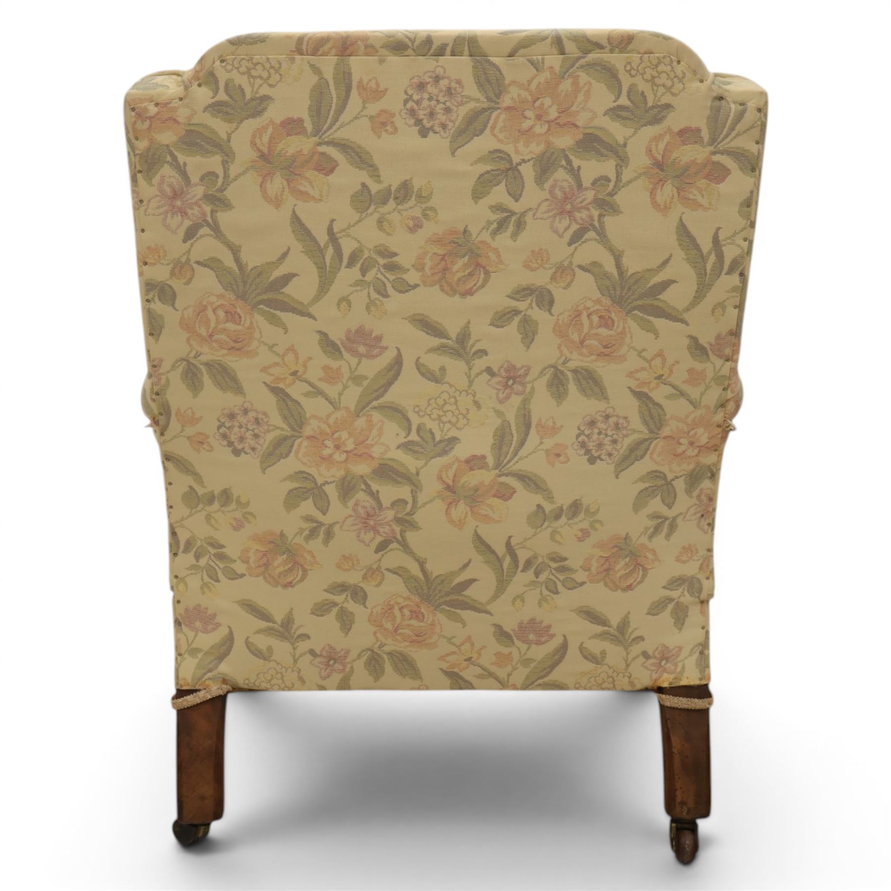 Victorian mahogany framed deep seat low drawing room chair, upholstered in beige floral fabric, on turned supports terminating in castors