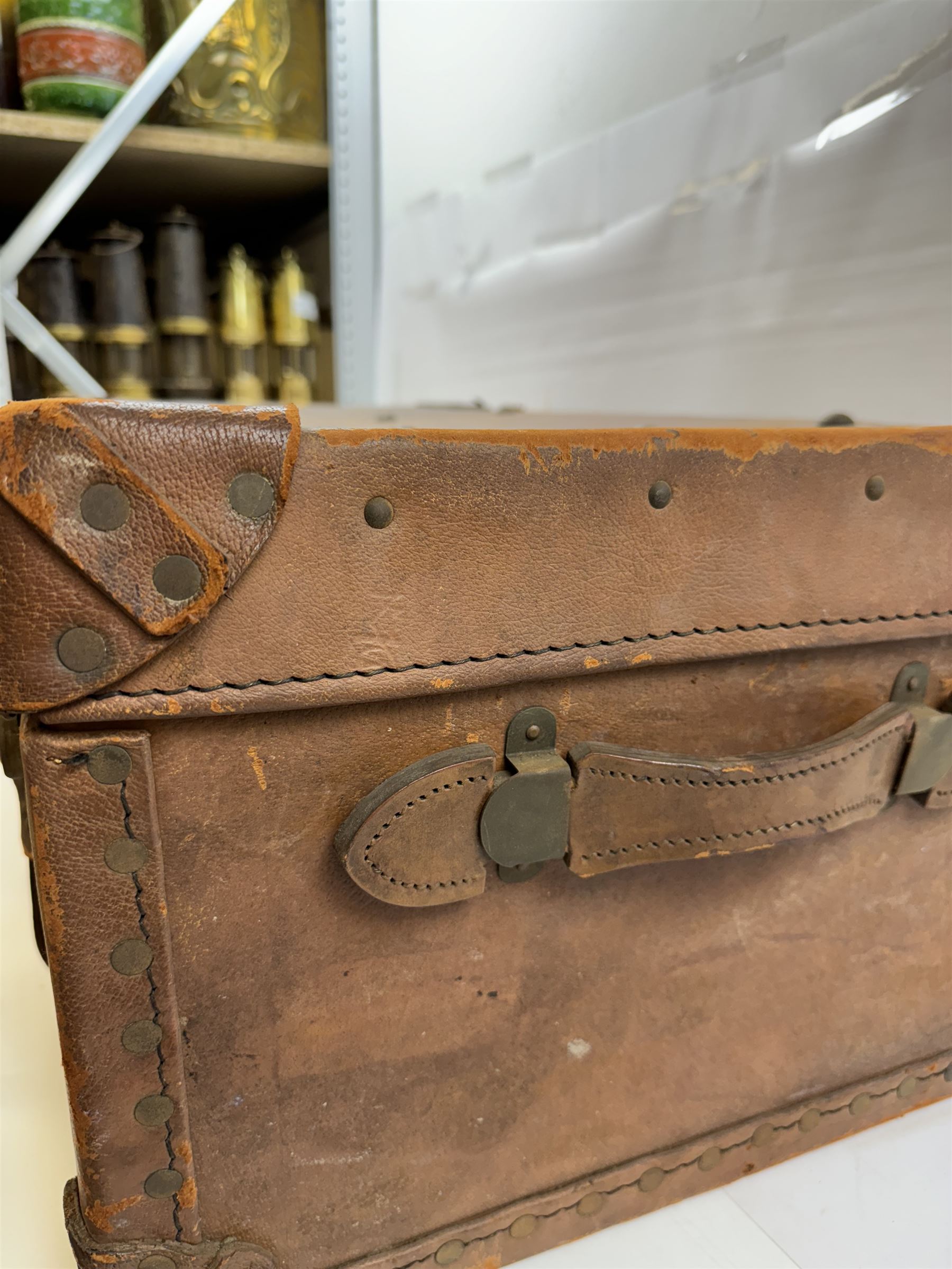 Early 20th century leather trunk, with brass fixtures, leather straps and buckle fastenings, embossed to the top with initials GG, H28cm, W76cm