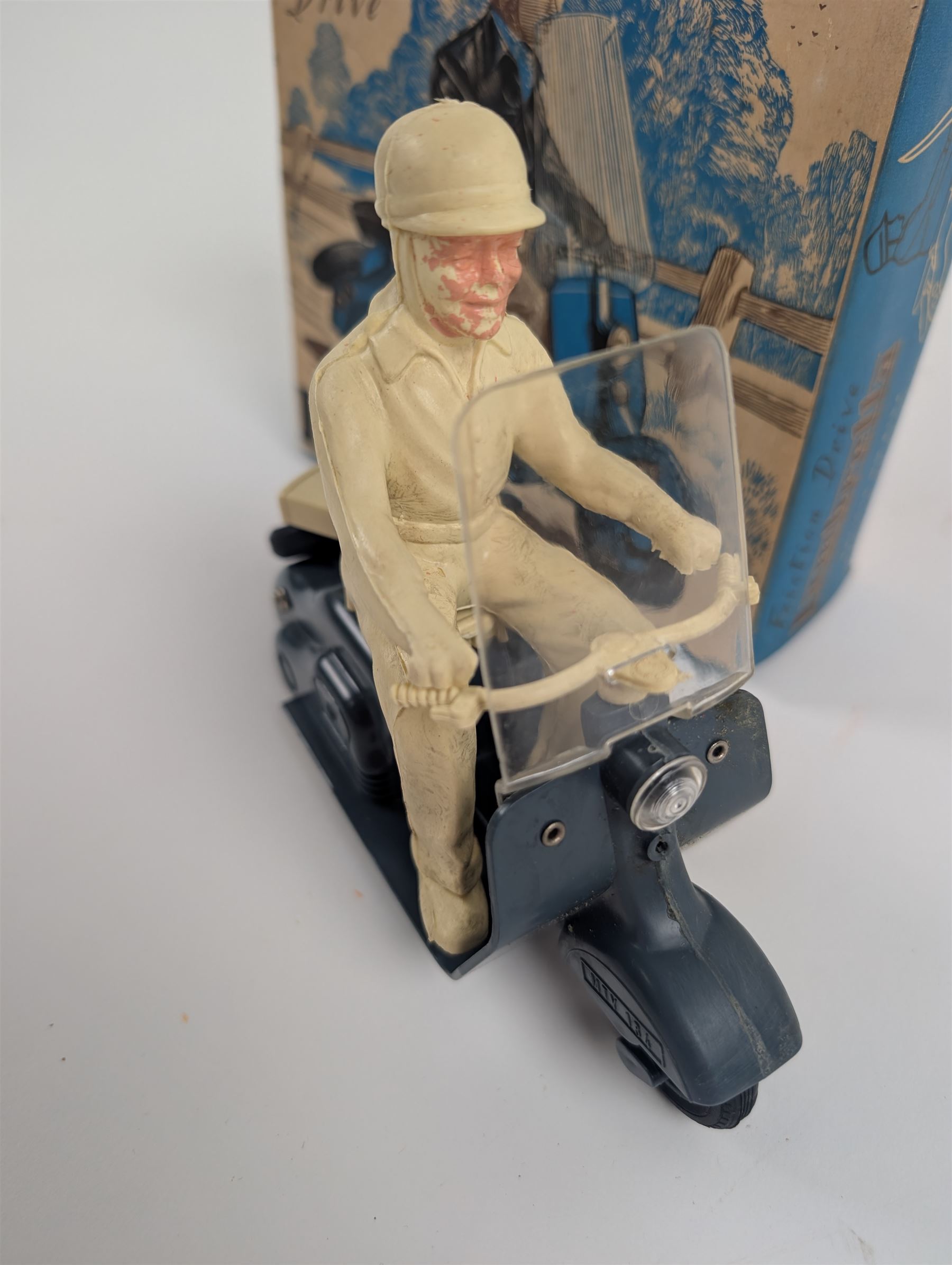 Mettoy friction drive Lambretta scooter no. 8134, the blue plastic scooter with cream handlebars and clear windshield, the rider with cream hat and clothing, stamped MTY 143 to front mud guards, in original box