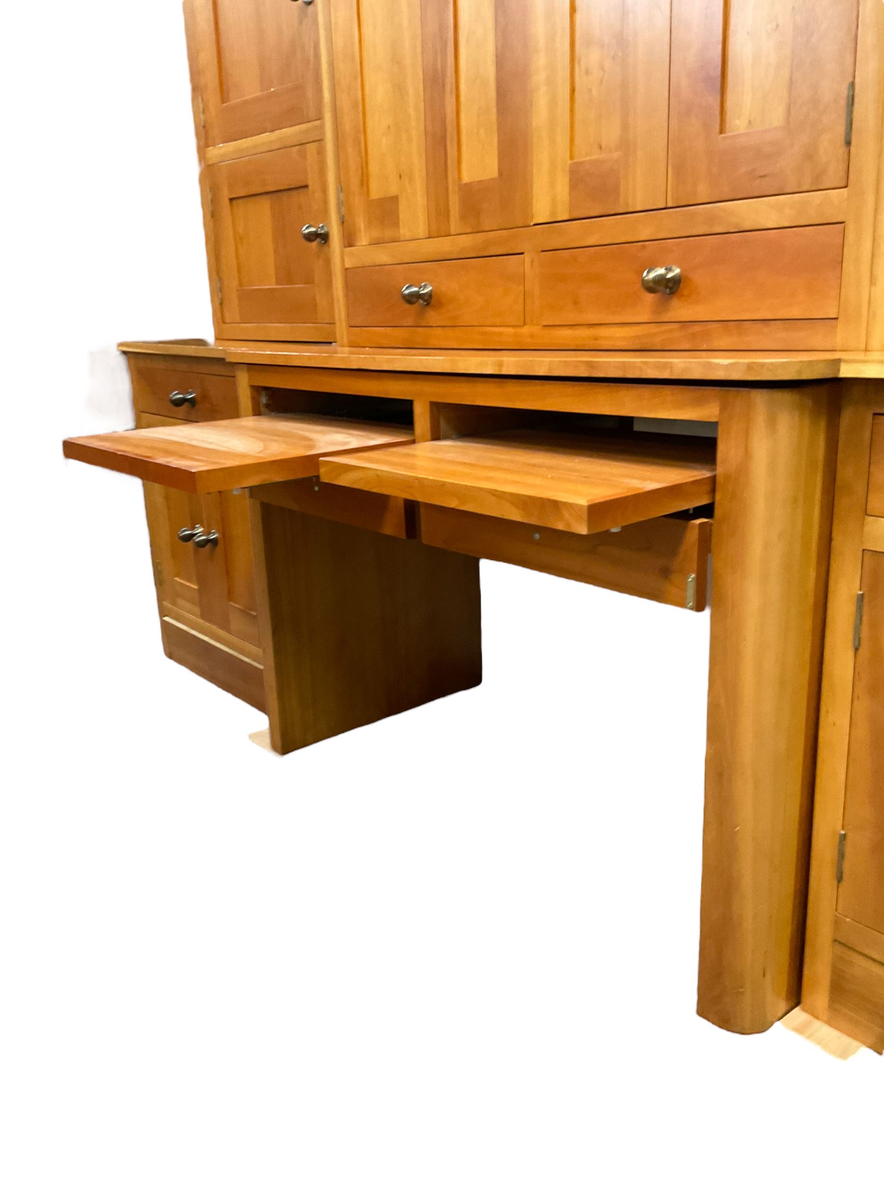 Large contemporary cherry wood break-front wall unit, the banded cornice over double cupboard with bifold doors and two drawers, flanked by four single cupboards, the base fitted with four drawers over four cupboards (W263cm, H216cm, D68cm); and a cherry wood cabinet, fitted with double cupboard over two short and two long drawers, with faux drawer facias (W81cm, H138cm, D66cm)