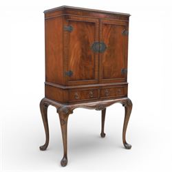 20th century Queen Anne style mahogany cocktail cabinet, moulded cornice above a pair of fielded panel doors with decorative strap hinges and central escutcheon, opening to a mirrored interior fitted with tiered shelves with brass gallery rails, pull-out glass inset mixing slide above three short drawers, shaped apron on cabriole supports with carved shell knees terminating in pad feet