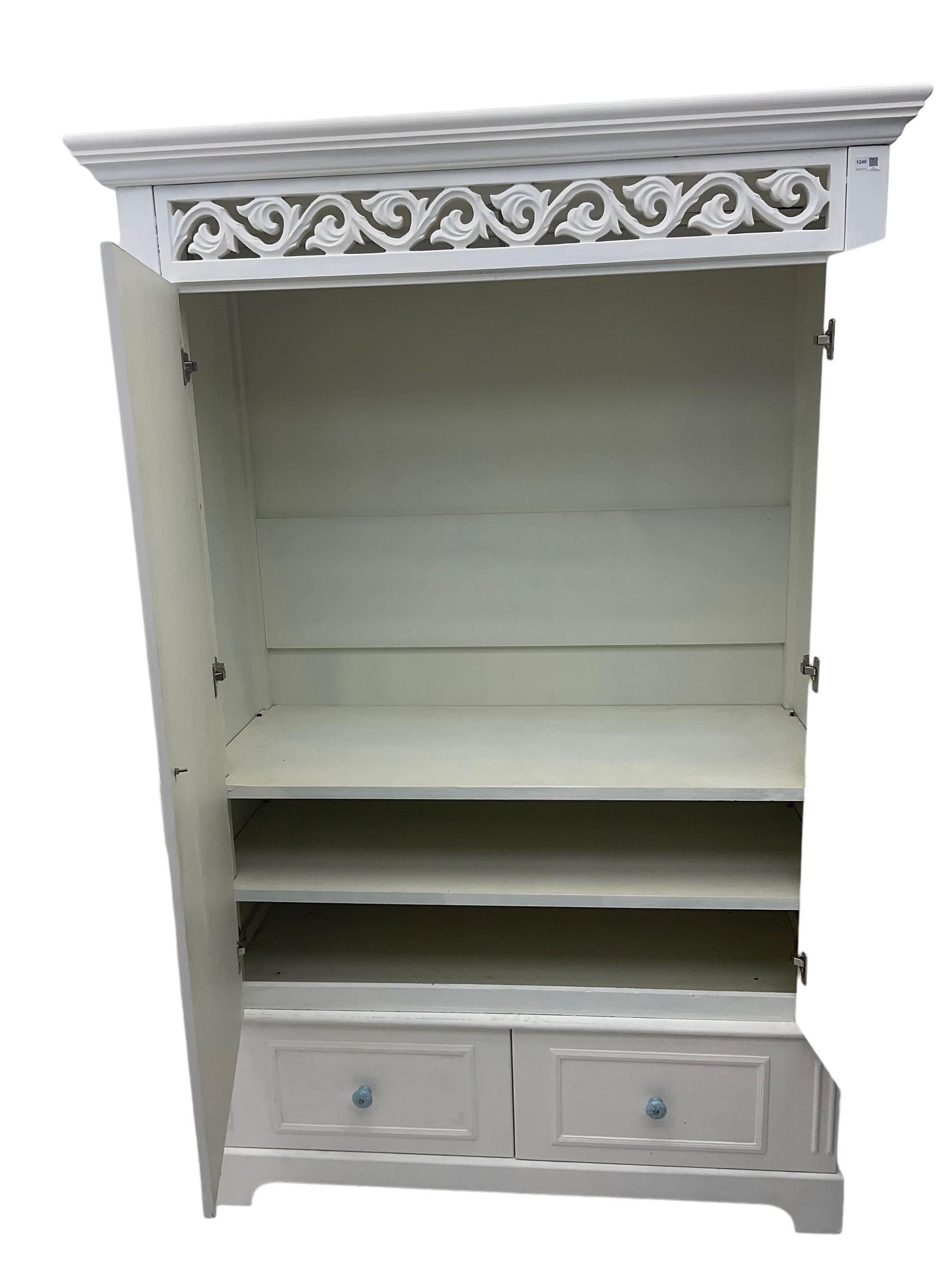 White painted double wardrobe, pierced scrolling foliate frieze over two doors enclosing hanging rail and two shelves, two drawers fitted to base, with blue ceramic handles