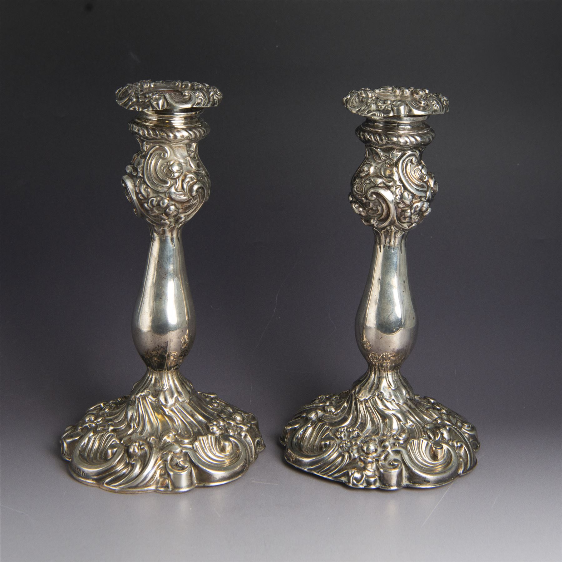 Pair of late Victorian silver candlesticks, each embossed wth floral, foliate and scrolling decoration, with removable sconces and upon a weighted embossed base, hallmarked Jenkins & Timm, Sheffiled 1891, H20cm