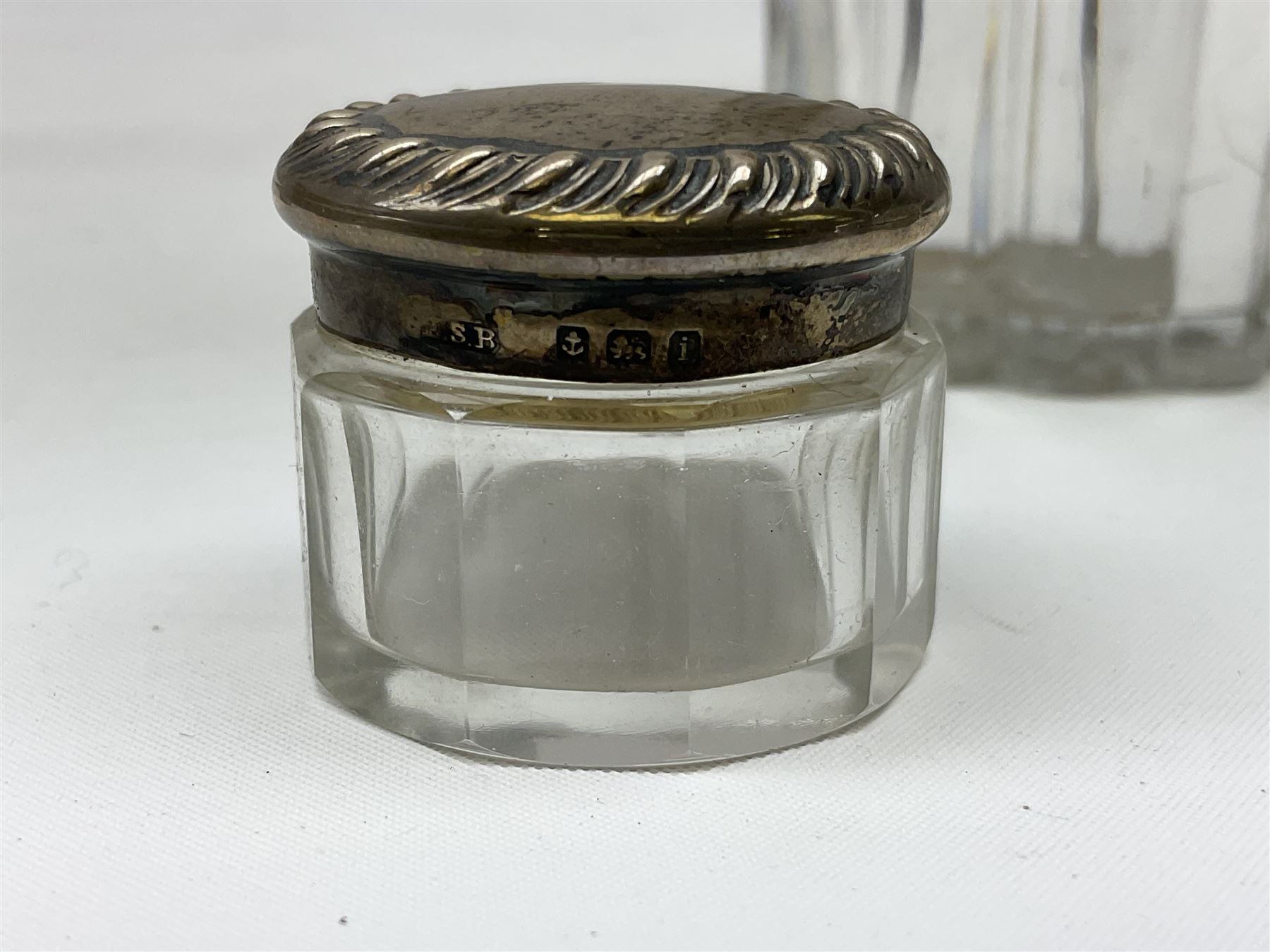 Edwardian silver mounted purse, with circular panel engraved with initials, and hammered finish, hallmarked William Comyns & Sons, London 1903, H14cm, together with three dressing table glass jars with hallmarked silver covers, and a hallmarked silver mounted buffer 