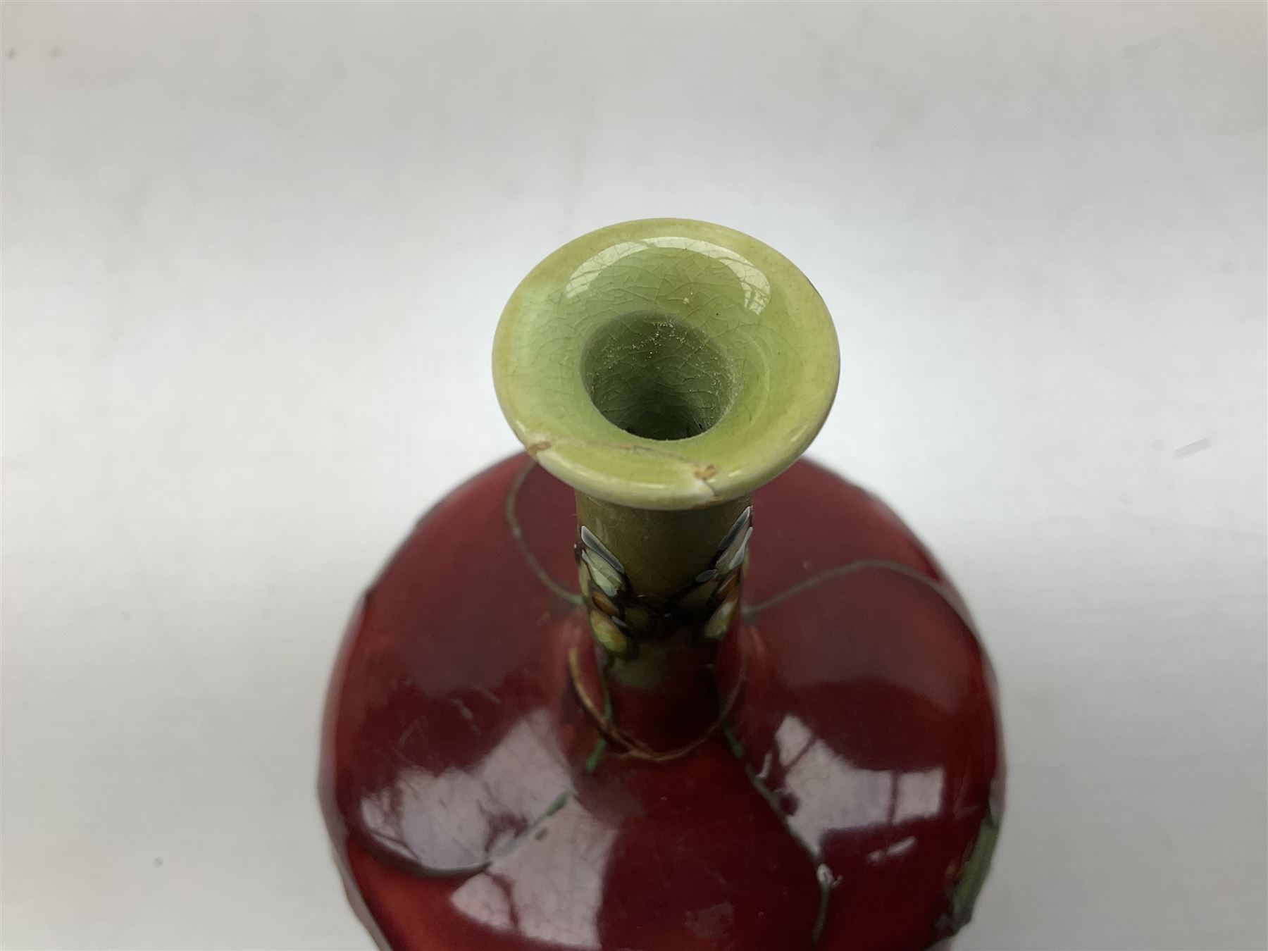 Three Minton Secessionist vases, with tube-lined stylised flower decoration, two upon a red ground and third upon a purple ground, all with printed mark to base 'Minton Ltd, No. 33', H13cm