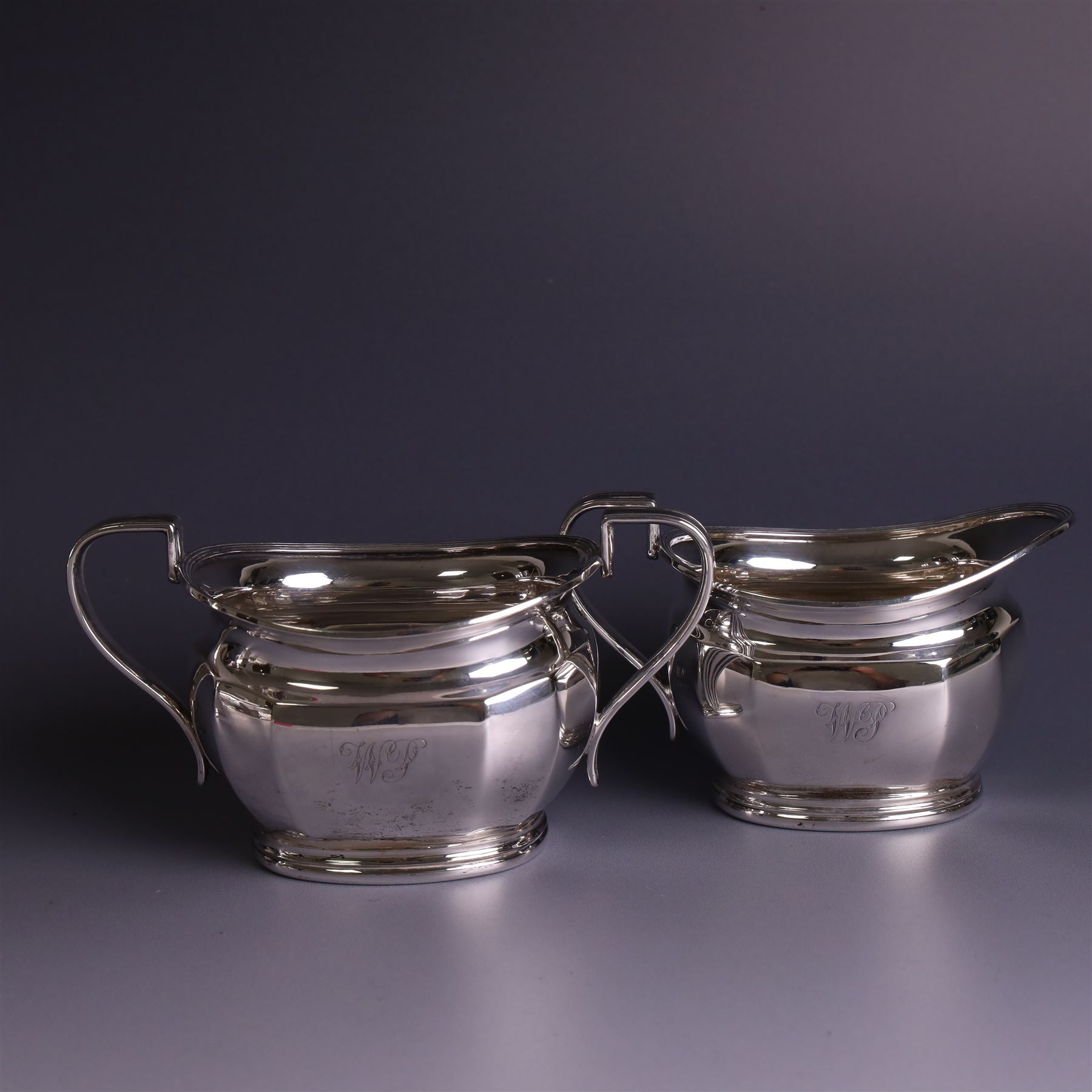 1930s silver four piece tea service, comprising teapot, hot water pot, sugar bowl and milk jug, each of part faceted oval form with engraved monogram to body, the teapot and hot water pot with Bakelite type handles and finials, hallmarked Atkin Brothers, Sheffield 1933