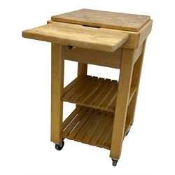 Beech butcher block kitchen cart, featuring square butcher block top, side drop-leaf extension, single drawer with metal sides, and two slatted shelves below, the cart supported by four castors