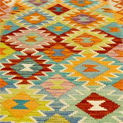 Afghan Chobi kilim flatweave runner with a repeating stepped diamond medallion design in live green, rust, teal, purple, and ivory, framed by chevron and geometric borders