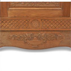 Early 20th century French oak triple door armoire, the moulded top above a frieze with carved lozenge decoration and central rosette, the central mirrored door enclosed by carved surround with floral crest, flanked by panelled doors with lattice carving, the base with shaped apron centred by carved basket motif, upon shaped cabriole supports