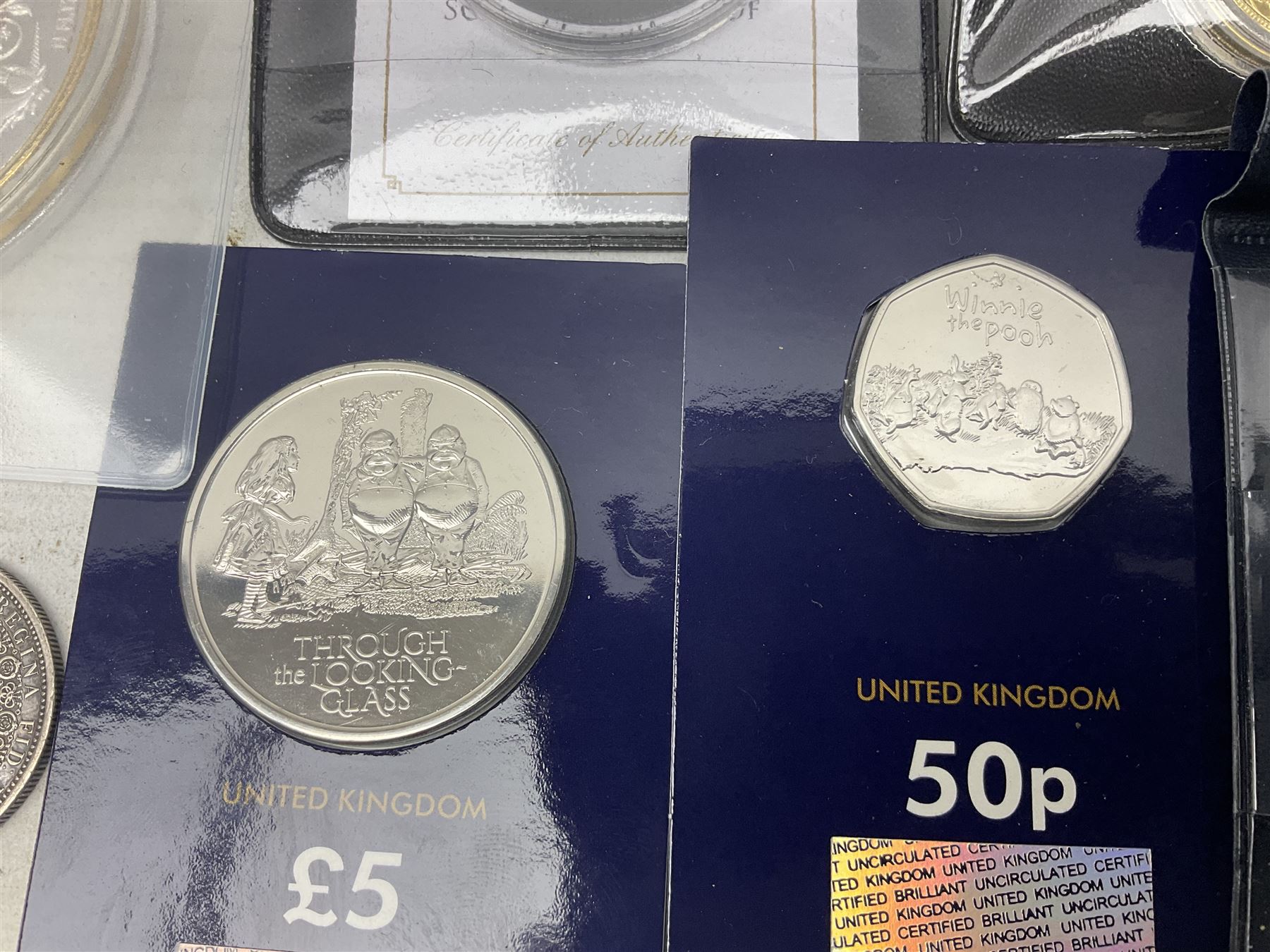 Coins and sets, including Great Britain and Northern Ireland 1970 proof coin collection in card folder, Queen Elizabeth II 2021 'Through the Looking Glass' five pounds, 2021 'Winnie the Pooh' fifty pence, Queen Victoria 1887 halfcrown, King George V 1914 halfcrown, commemorative coins, The Royal Mint Solomon Islands 2003 twenty-five dollars silver proof coin cased with certificate, 9ct gold half sovereign mount etc