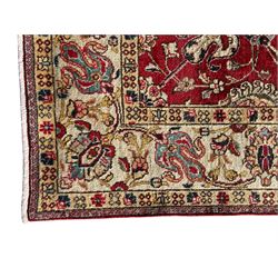 Persian Tabriz crimson ground rug, the field decorated with large palmette and stylised plant motifs connected by interlaced leafy branches, trailing border decorated with similar palmette motifs within floral pattern guard stripes, with signature panel 