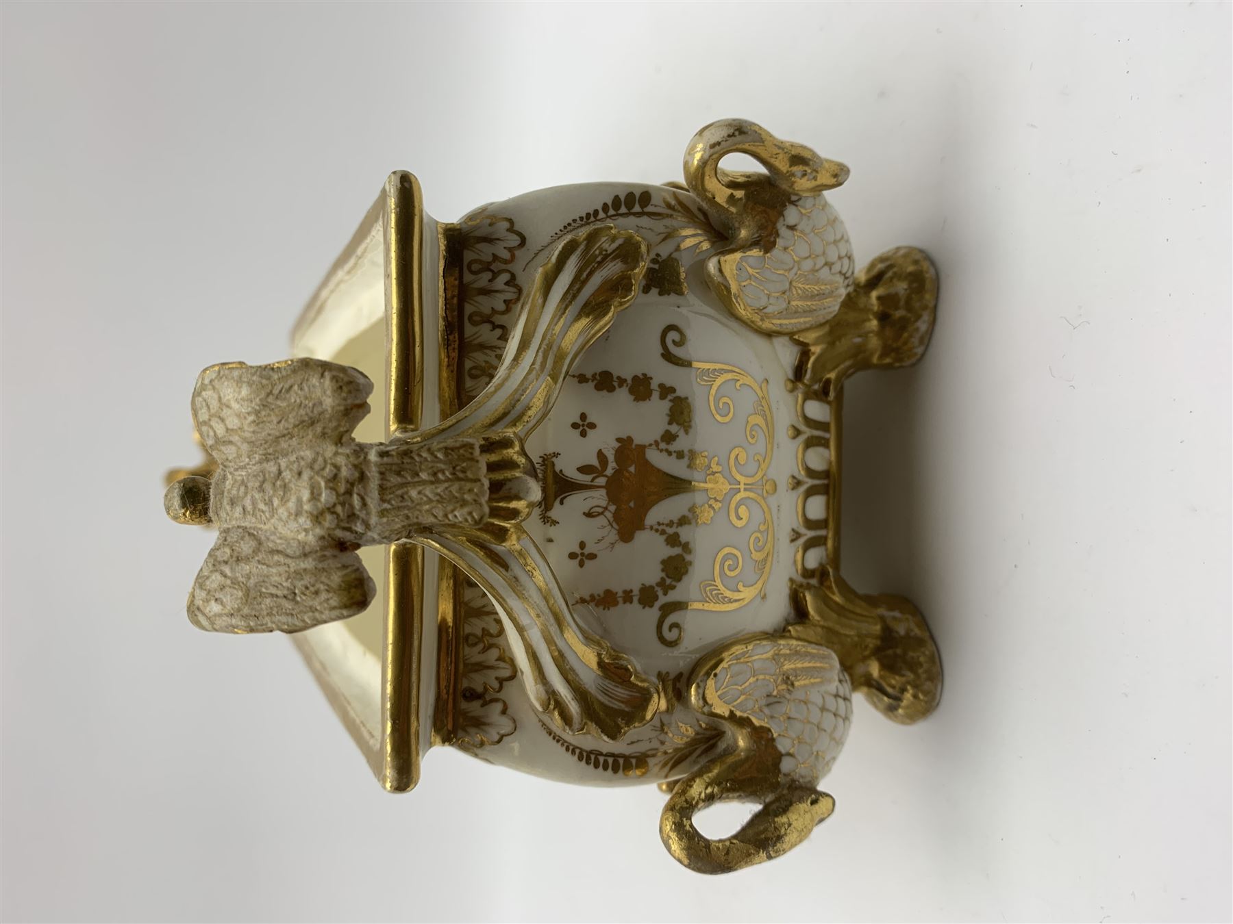 19th century Coalport bough pot, circa 1820, of bombe form, the body with twin handles surmounted by two birds and raised upon four feet modelled as swans, hand painted with two panels depicting an urn of flowers set against a mountainous landscape, the whole heightened in gilt throughout, H13cm L21cm