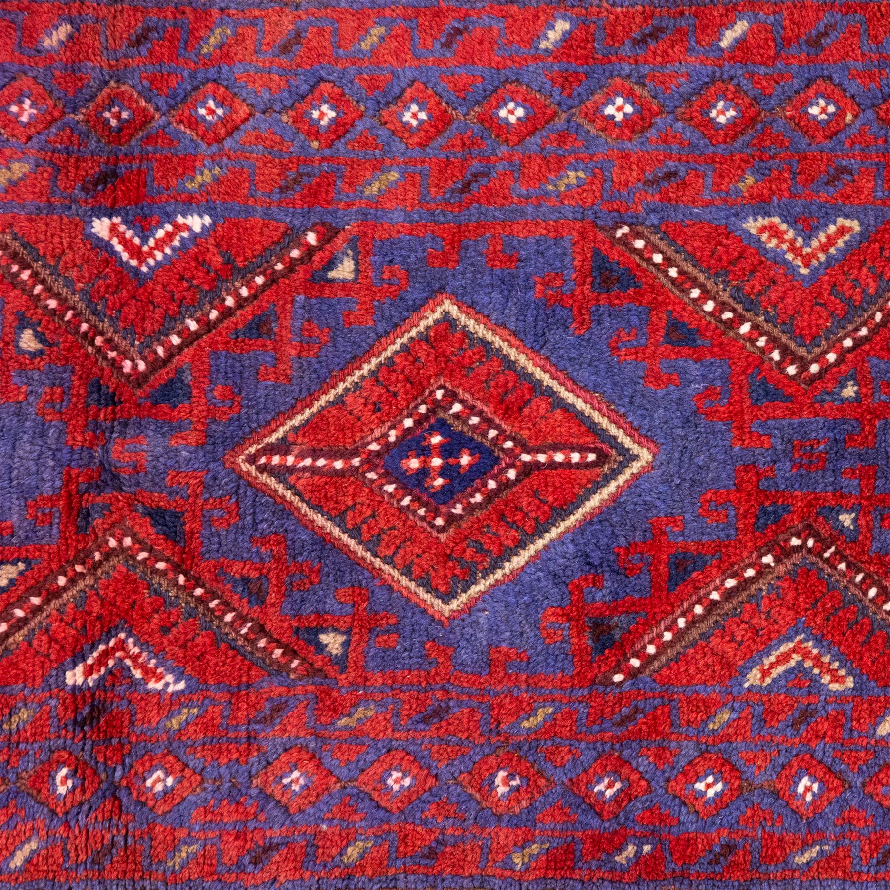 Afghan Meshwani runner, hand-knotted wool pile, indigo ground decorated with a vertical series of angular diamond medallions in tones of madder red, dark blue, framed by geometric borders with flatwoven kilim ends with fringe 