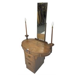 Art deco oak dressing table, raised back with rectangular swing mirror, oval top with flanking electric candlesticks, the frieze with central floral panel and two drawers, over two central drawers