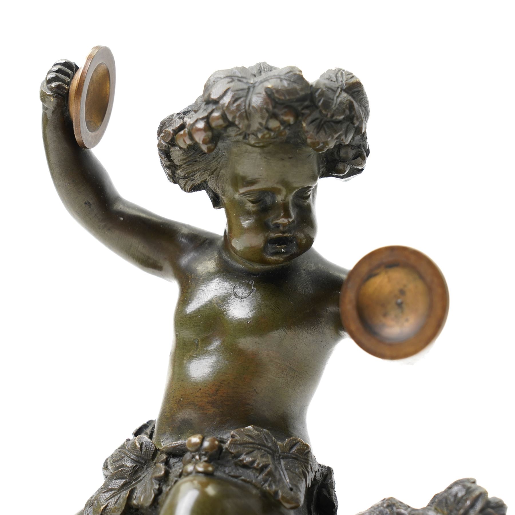 After Michel Claude Clodion (French 1738-1814): Grand Tour patinated bronze figure of a bacchic cherub, modelled dancing and playing cymbals, seated upon a naturalistic rocky base entwined with vine leaves and grapes, bearing signature, mounted on an oval red marble plinth, 19th century, W15cm H19cm