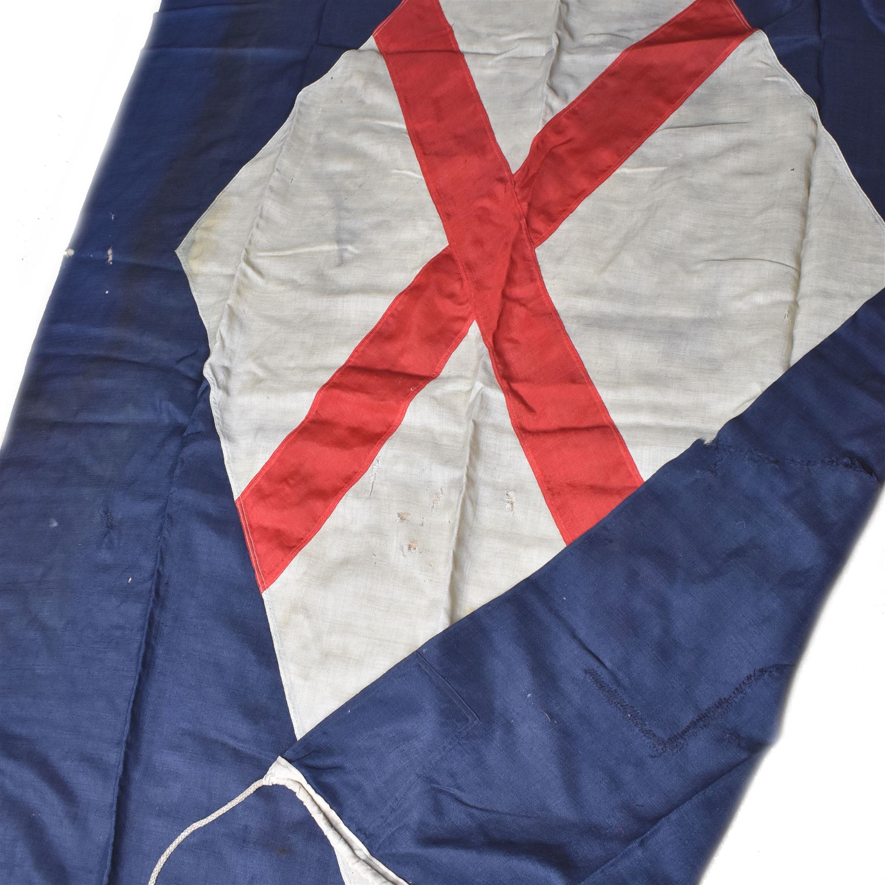 Ship's house flag, rectangular linen flag, with a white diamond and red cross to the centre, upon a cobalt blue ground, inscribed on the hoist 'Cutty Sark', H130cm, W170cm

Provenance by vendor repute: Vendor's father was a naval cadet in 1940s/50s on board HMS Worcester which was moored alongside the Cutty Sark on the River Thames at Greenhithe. He has had the flag since then. 