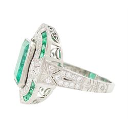 Platinum emerald and diamond milgrain set dress ring, single octagonal cut emerald of 2.40 carat, surrounded by single cut diamonds and a border of calibre cut emeralds, with fancy pierced design gallery diamond and engraved flower head shoulders, stamped 850 Plat